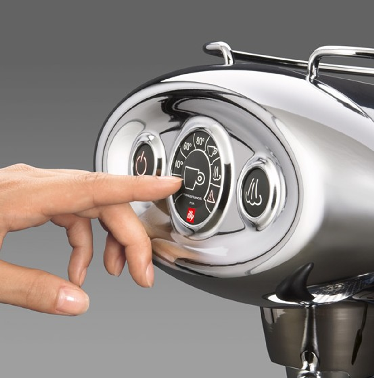 Ręka osoby naciskająca przycisk na chromowanym ekspresie do kawy. Ma pokrętła.