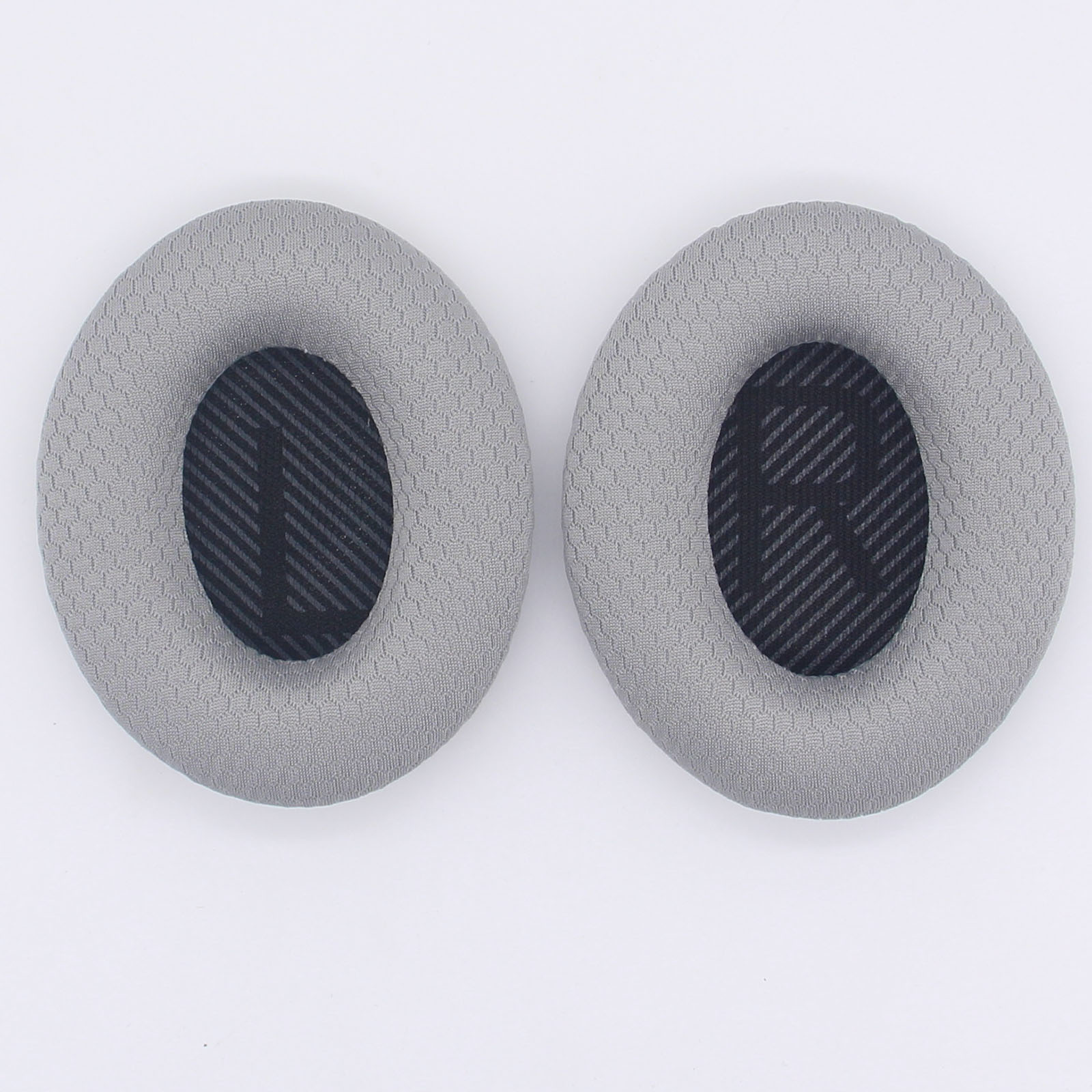 Due cuscinetti auricolari grigi a forma ovale con centri in rete nera, su sfondo bianco.