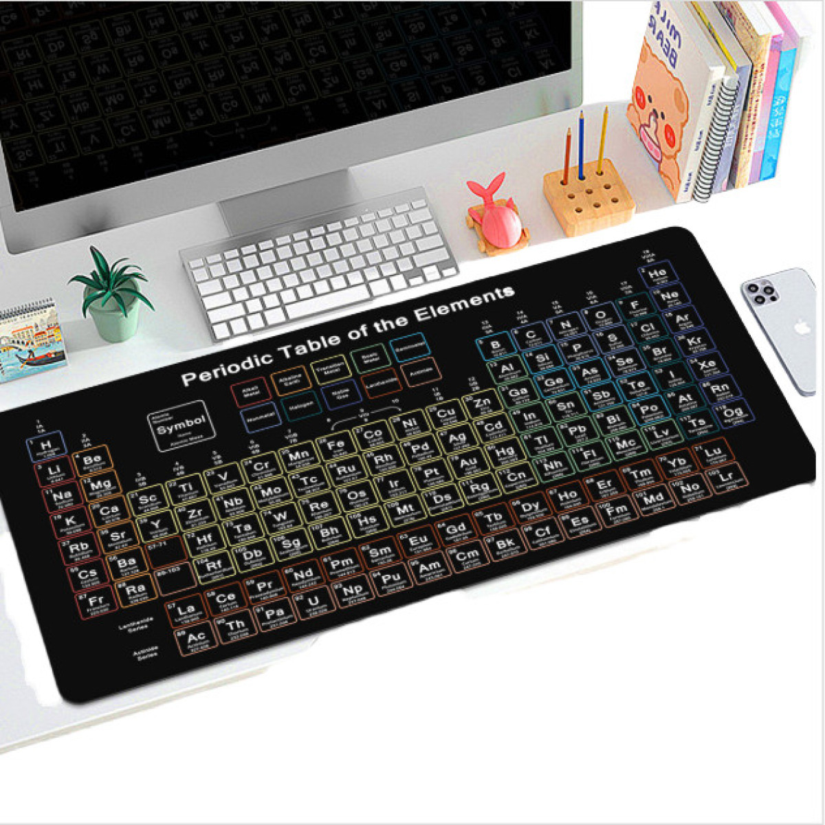 Bureau met periodieke tabel muismat, toetsenbord, pennen, telefoon en boeken. Witte achtergrond.