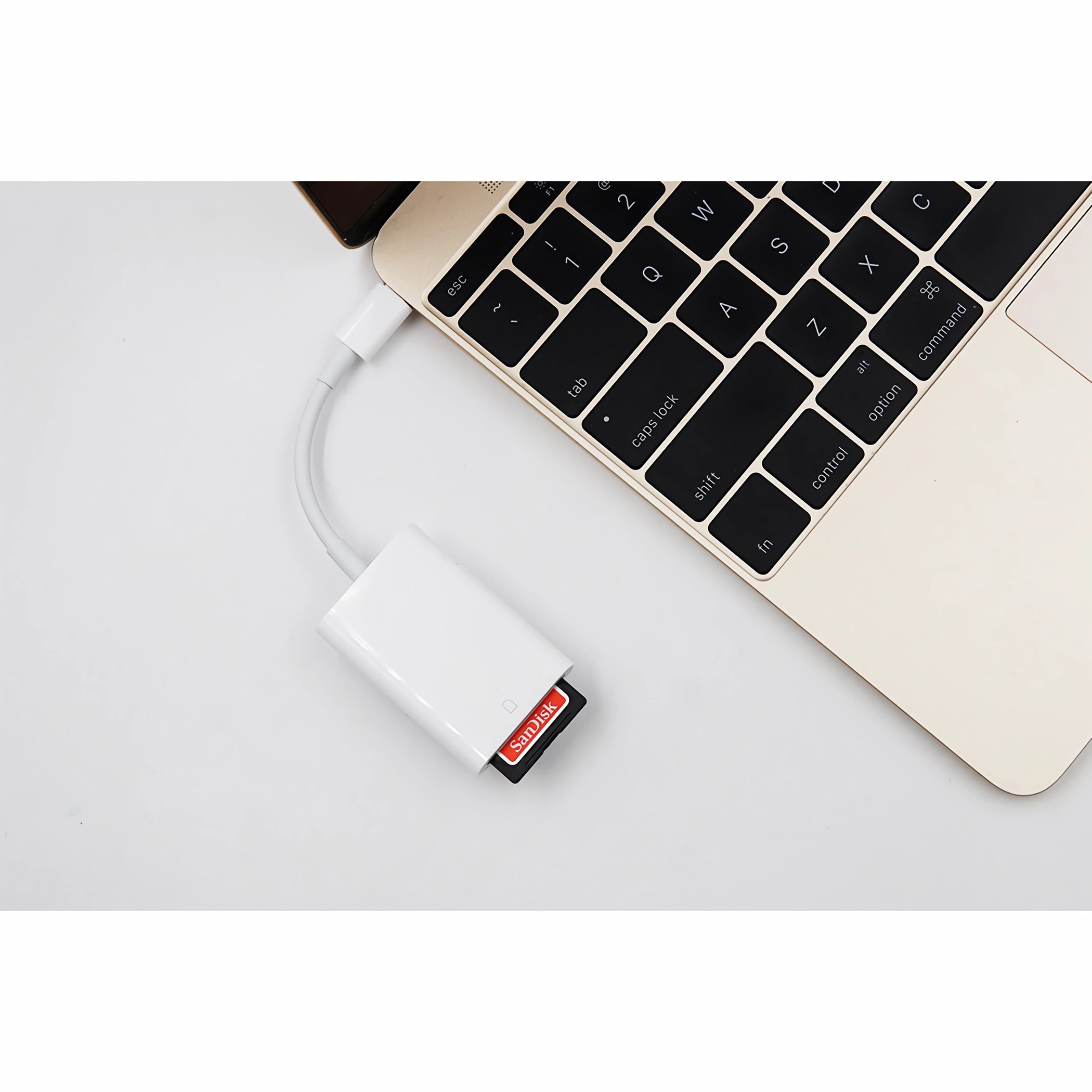 Laptop und ein weißer USB-Adapter mit eingesetzter Sandisk SD-Karte.