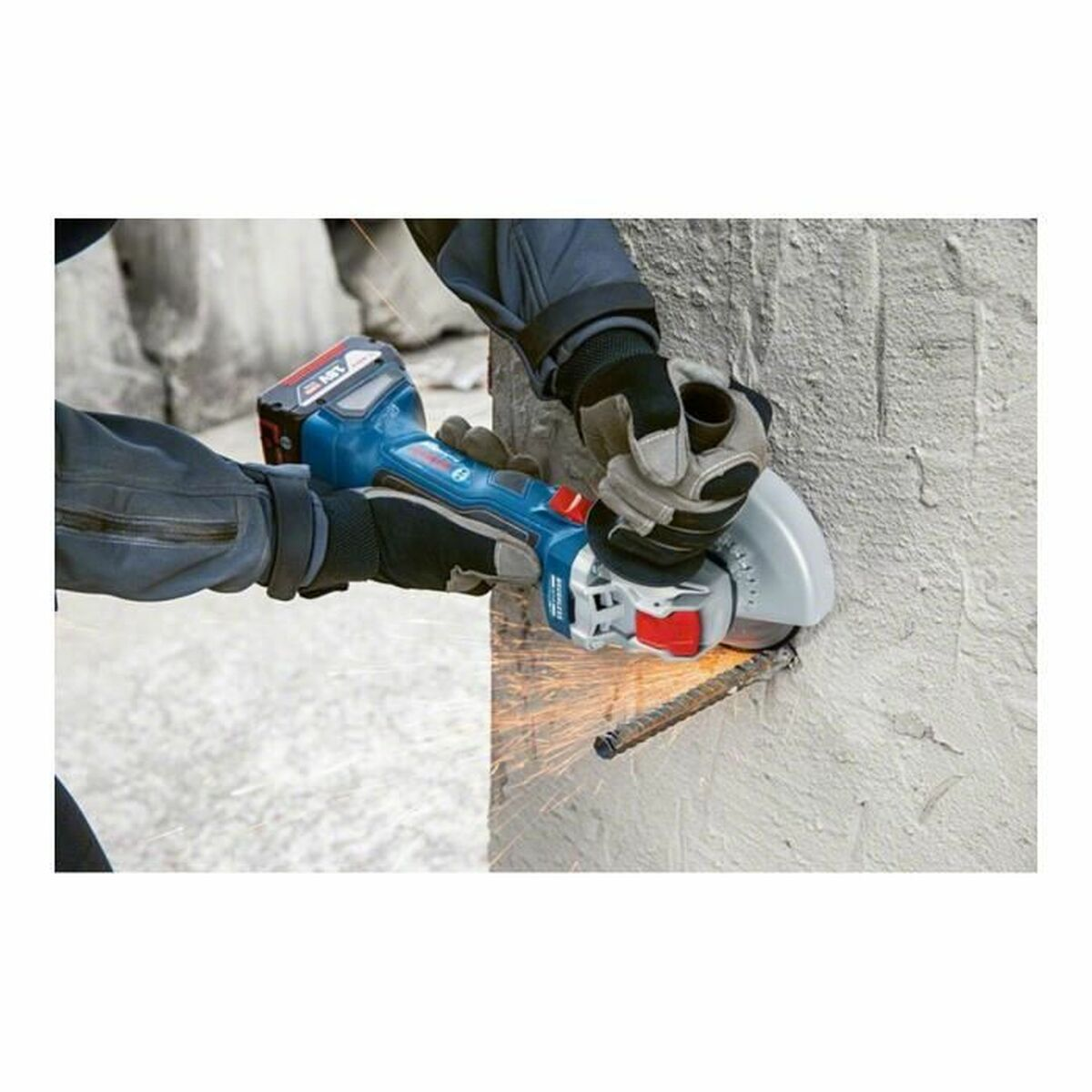 Osoba używająca szlifierki kątowej do cięcia pręta zbrojeniowego, iskry, betonowe tło.