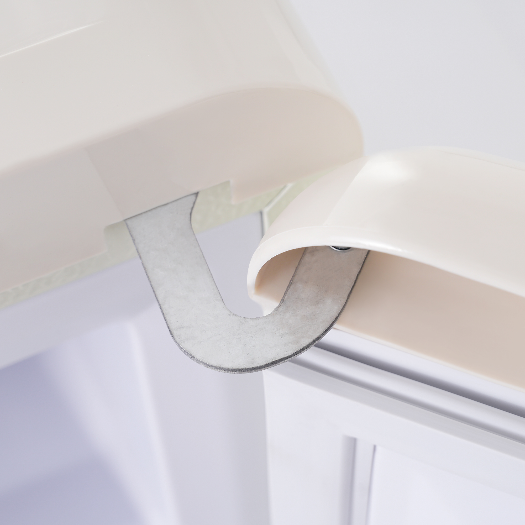 Nahaufnahme eines Metallscharniers, das zwei cremefarbene Oberflächen verbindet, mit U-förmigem Design.