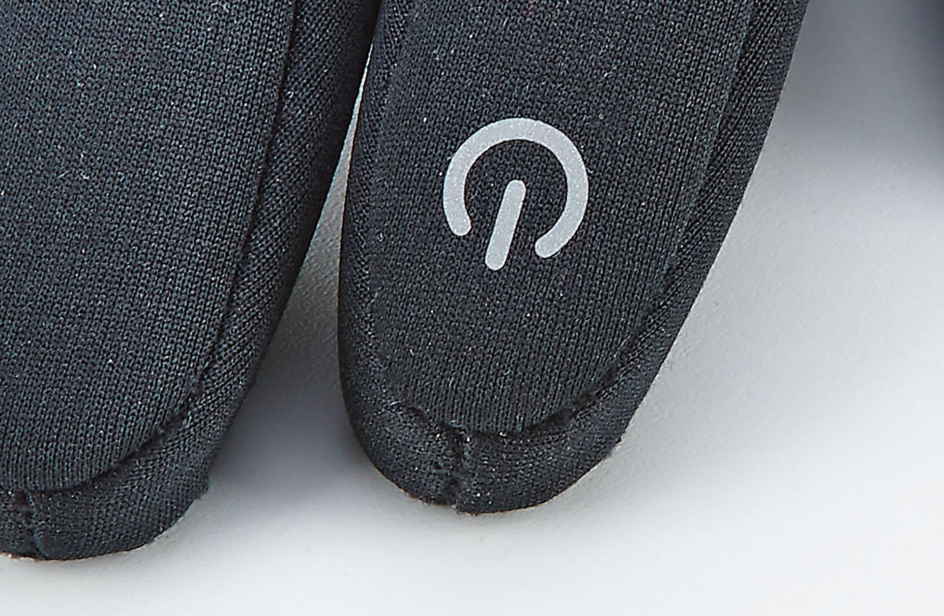 Schwarzer Handschuh mit weißem Power-Symbol. Fokus auf den Handgelenkbereich.