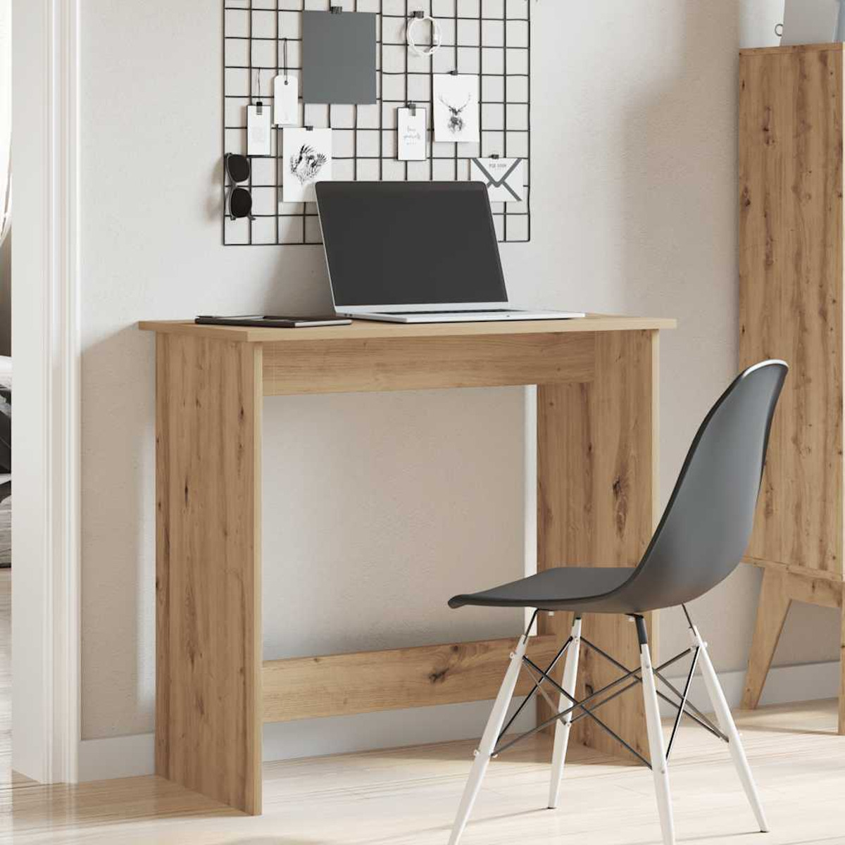 Holzschreibtisch mit Laptop, Stuhl und Wand mit Notizen. Der Schreibtisch steht vor einer Wand.