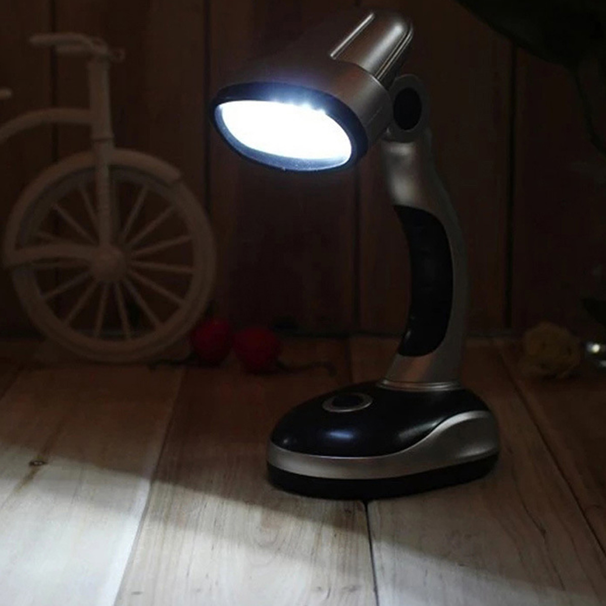 Eine silberne Schreibtischlampe mit hellem Licht, die auf einer Holzoberfläche steht.