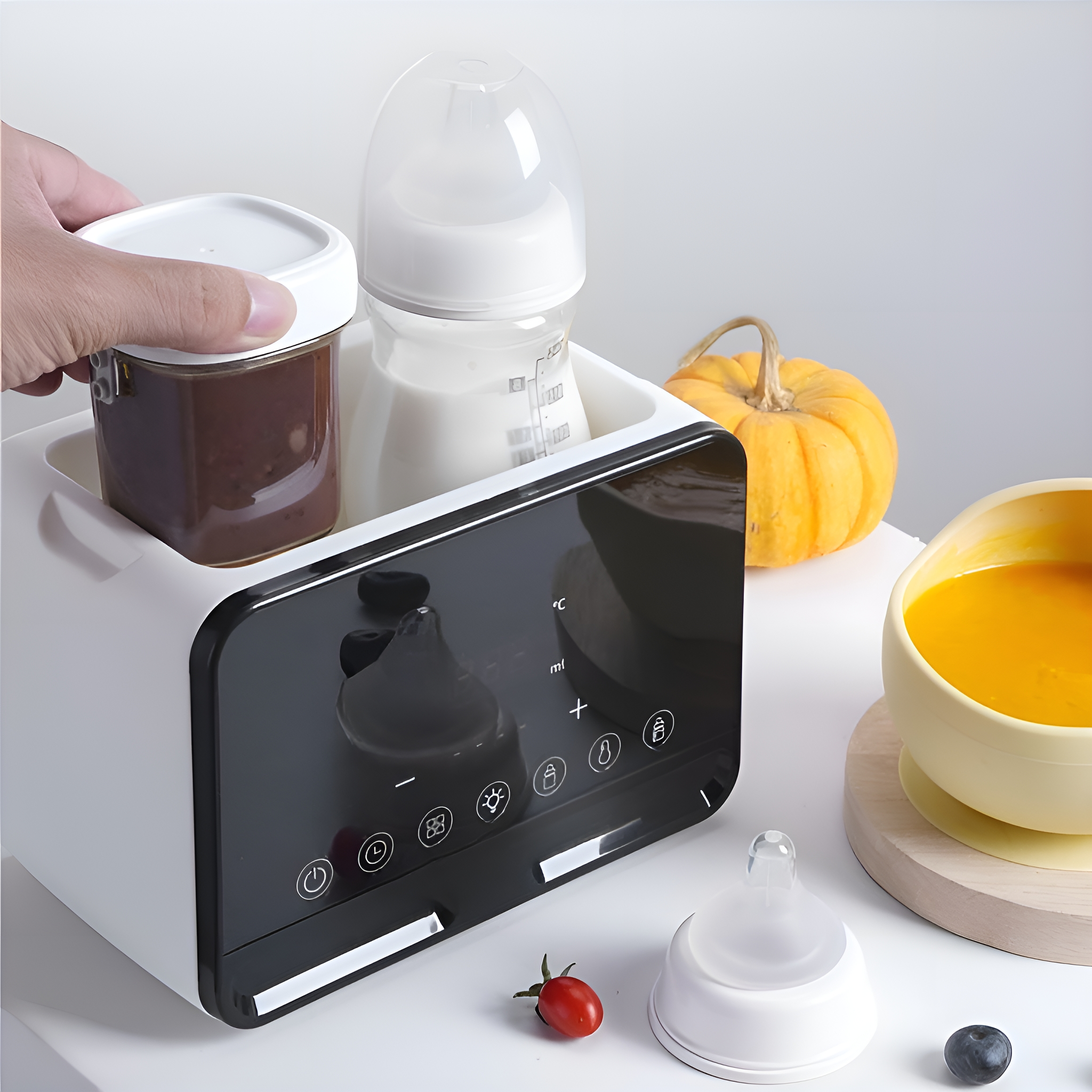 Ein weißer Babyflaschenwärmer mit schwarzem Display, hält eine Babyflasche und ein Gläschen. Eine Schüssel mit Essen.