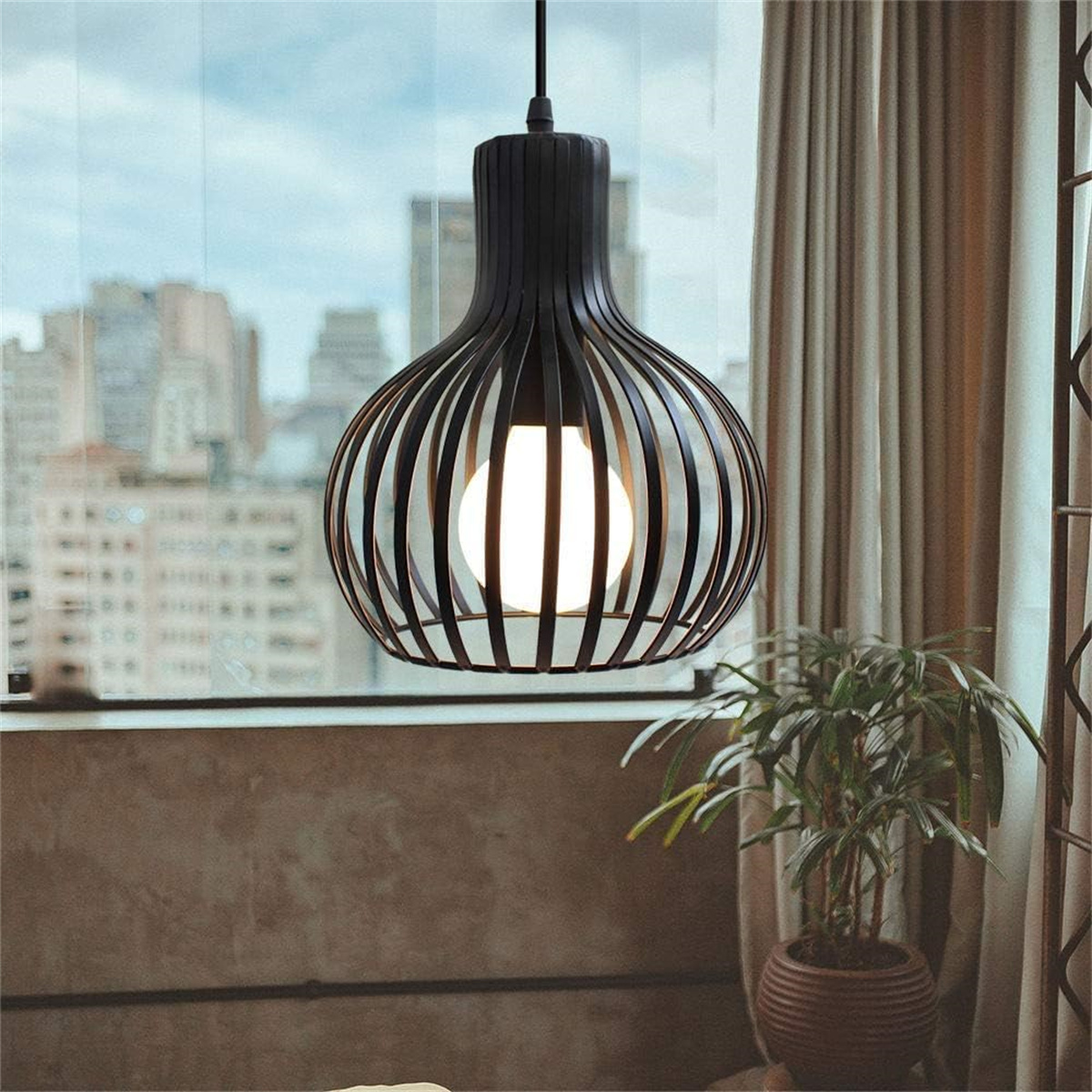 Schwarze Pendelleuchte. Offenes Design mit weißer Glühbirne. Vor einem Fenster.