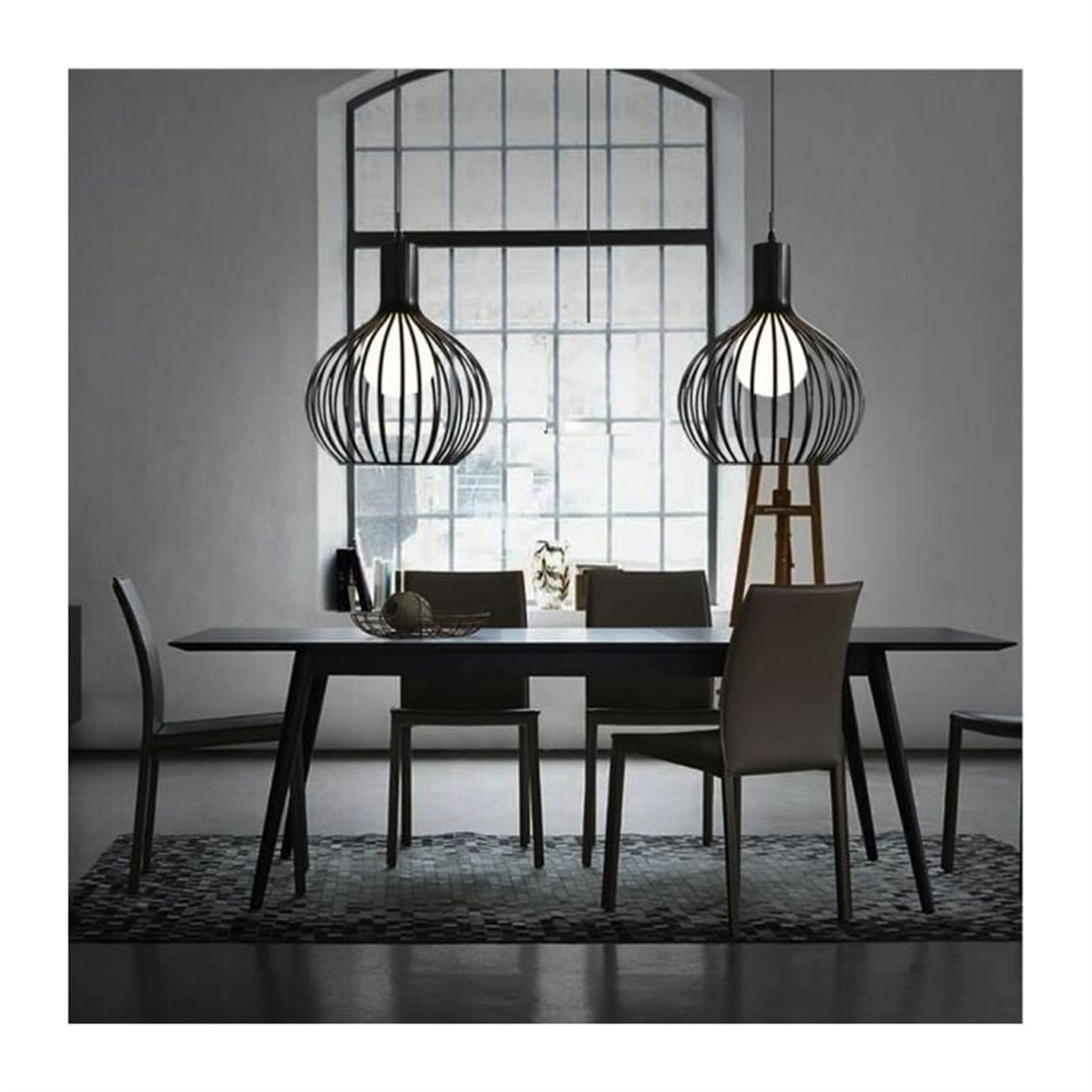 Zwei schwarze Lampen hängen über einem Tisch. Ein Fenster im Hintergrund.