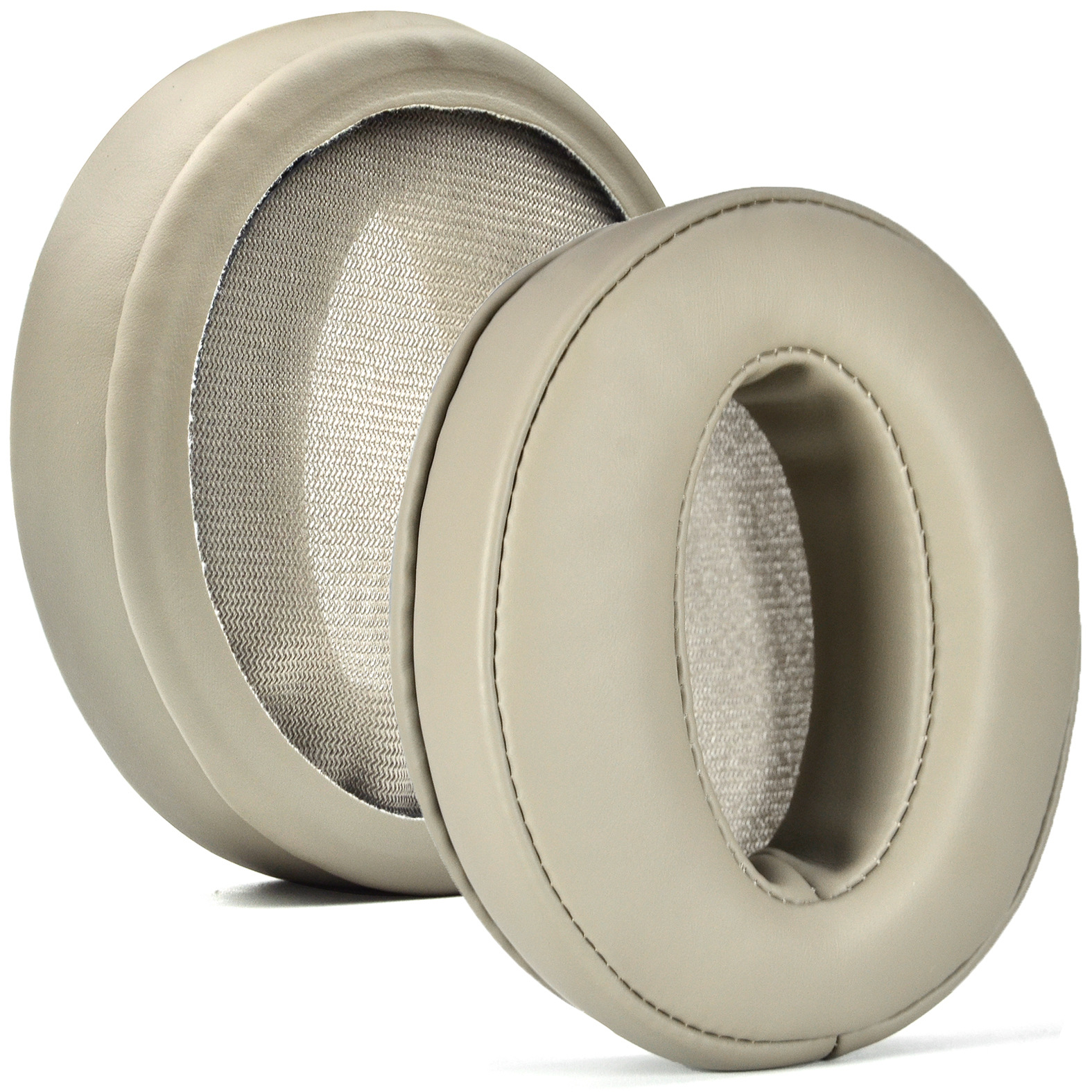 Twee beige oorkussens voor koptelefoons. Eén is gedraaid om het binnenste gaas te laten zien.