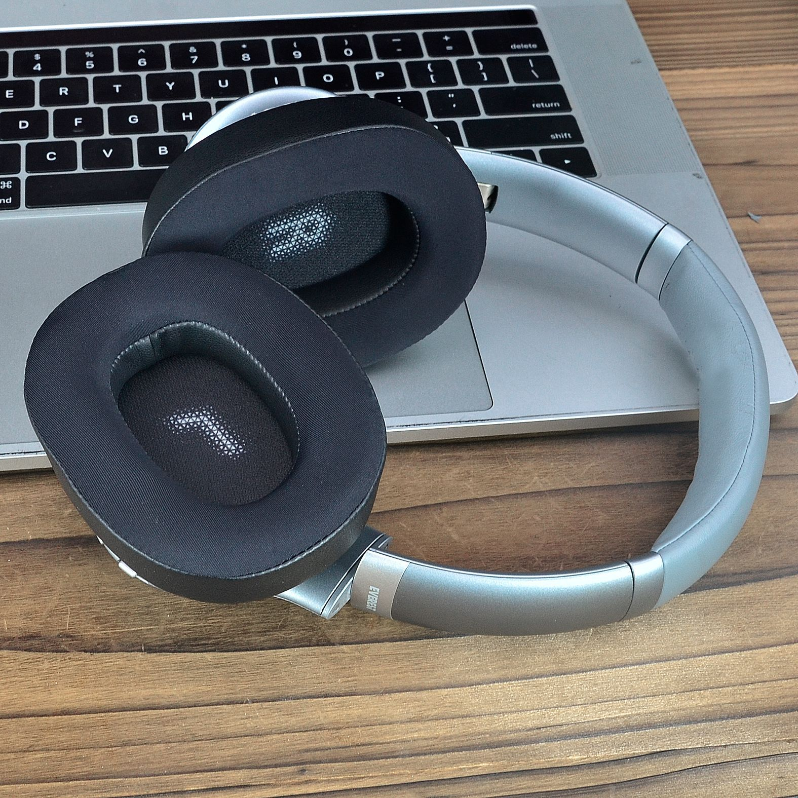 Srebrne słuchawki na klawiaturze laptopa. Słuchawki mają czarne nauszniki i srebrny pałąk.