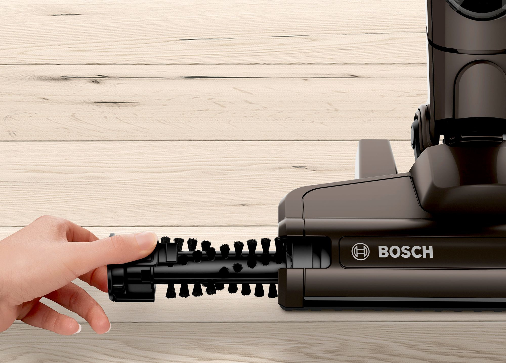 Mano che tiene un rullo spazzola di un aspirapolvere. Logo Bosch sul corpo.