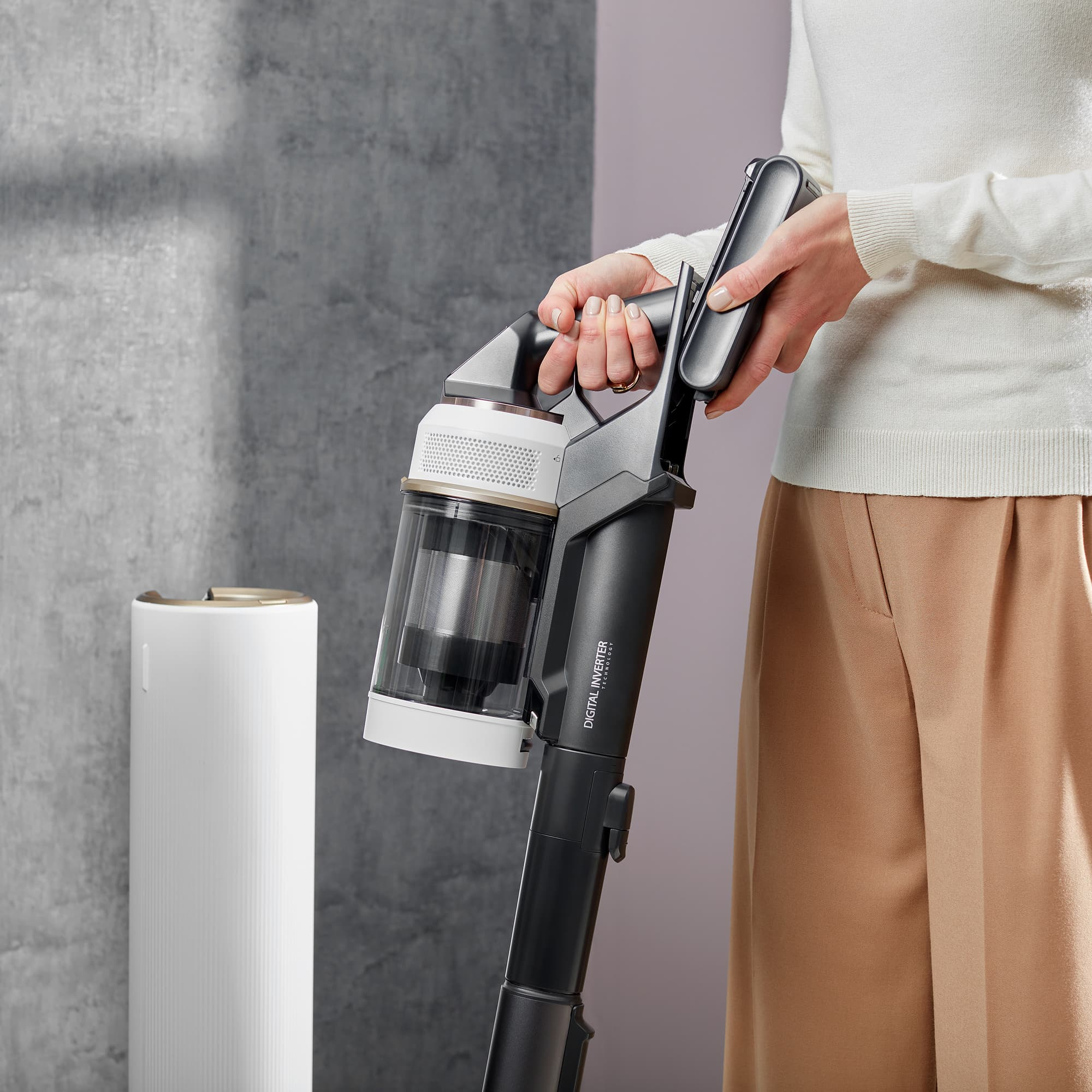 Eine Person hält einen schwarz-weißen kabellosen Staubsauger.