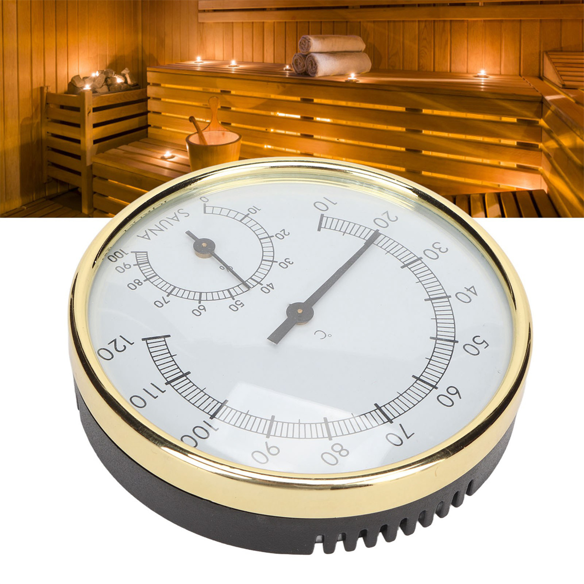 Ein Saunathermometer mit Goldrahmen, vor verschwommenem Saunahintergrund.