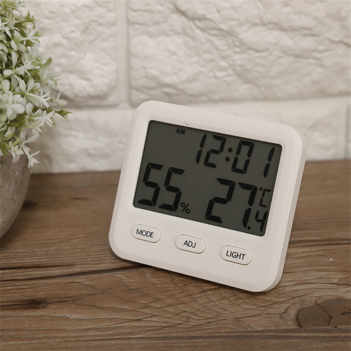 Eine weisse Digitaluhr mit Zeit- und anderen Daten. Sie steht auf einer Holzoberfläche.