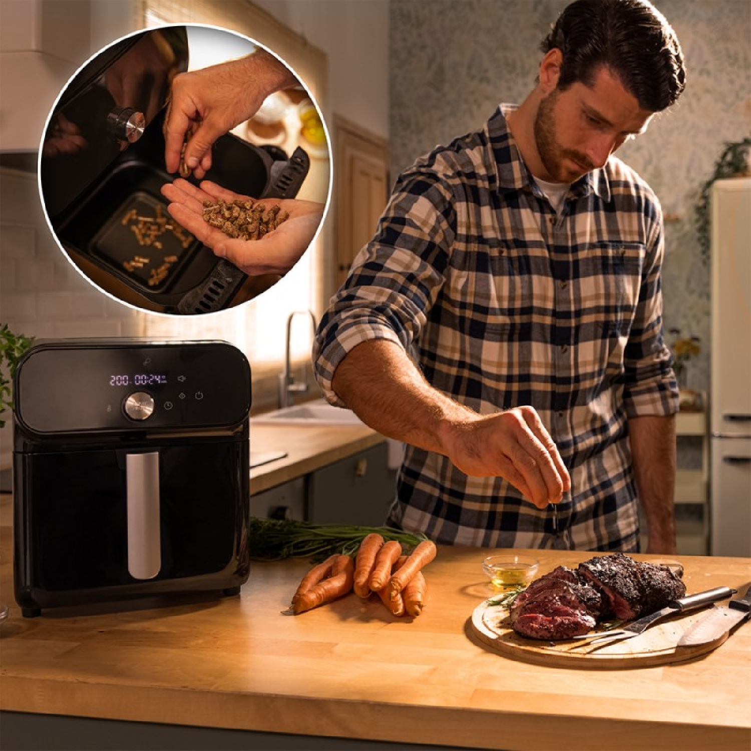 Hombre en la cocina preparando comida con una freidora de aire. Zanahorias y bistec en la encimera.