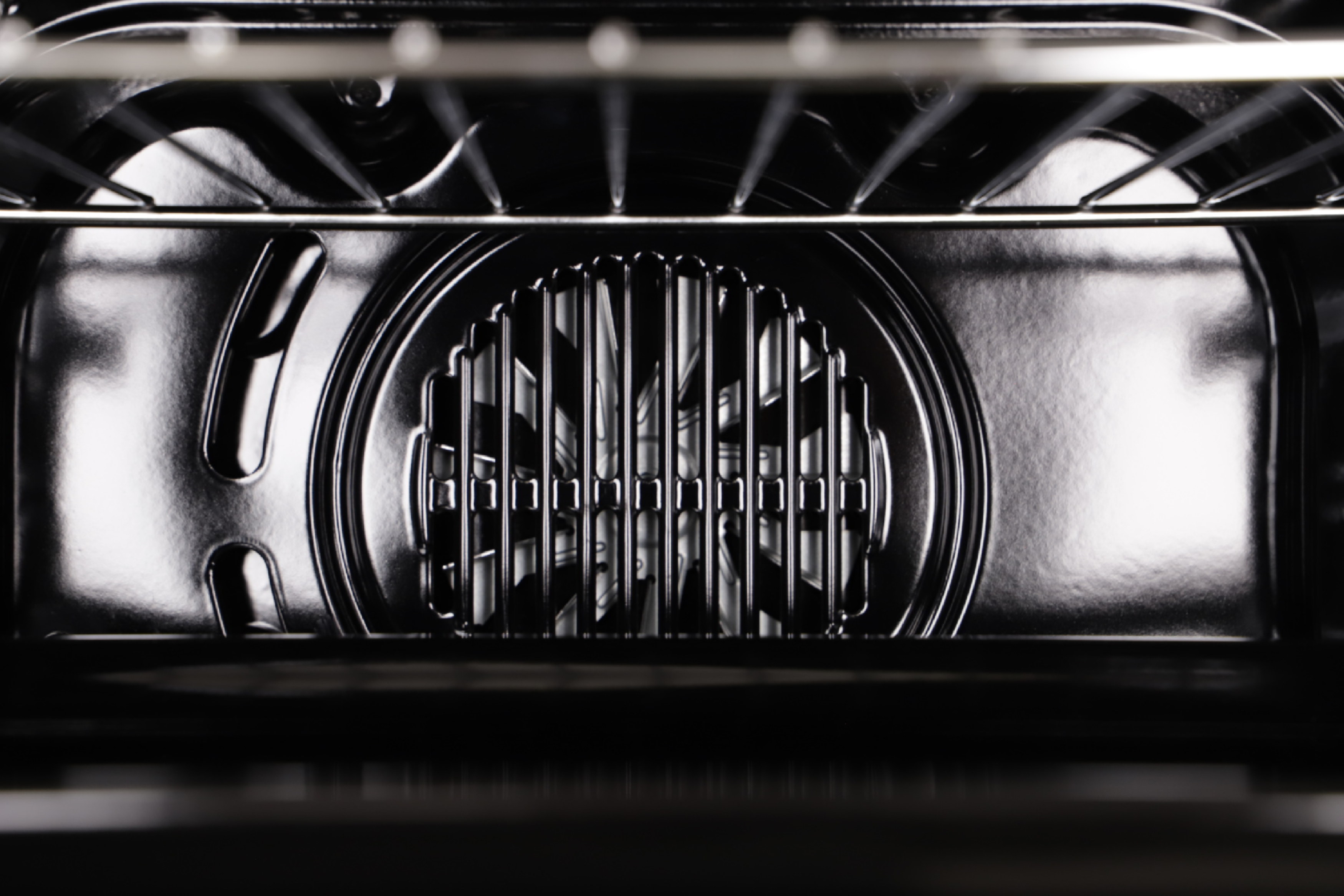 Im Inneren eines Ofens: ein Ventilator, Metallroste und schwarzes Innere. Die Ansicht ist von der Ofentür aus.