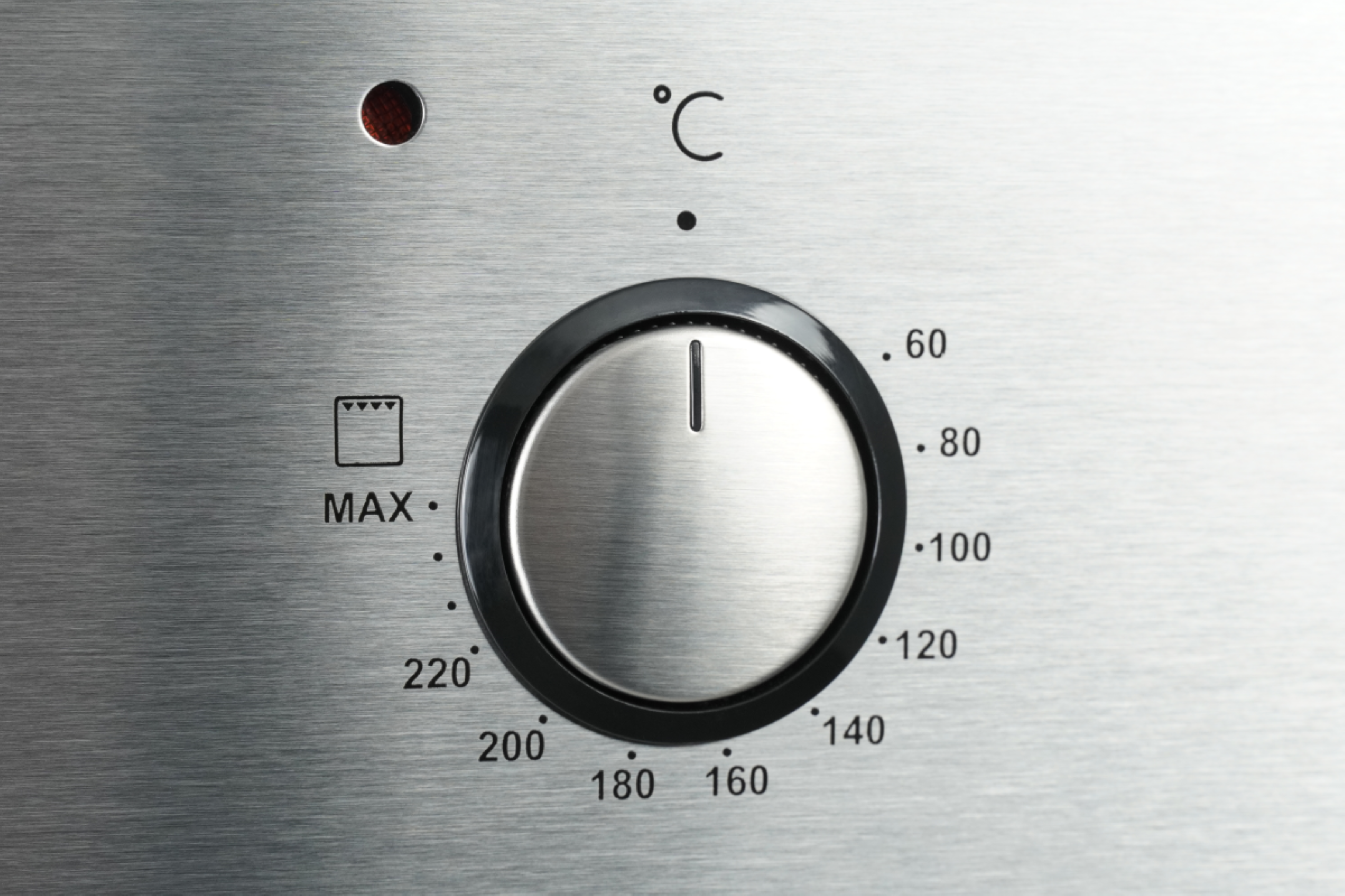 Nahaufnahme eines Ofen-Temperaturreglers. Das Zifferblatt ist schwarz und silber und hat Zahlen.