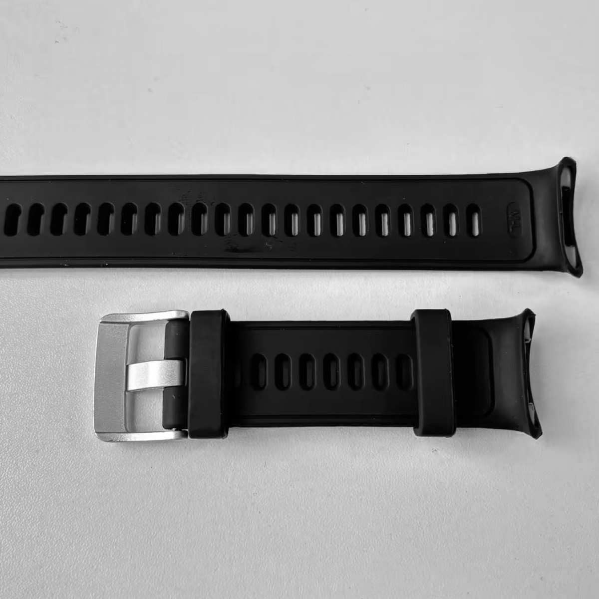 Dwa czarne paski do zegarka, jeden z otworami i metalowym zapięciem, drugi ze sprzączką.