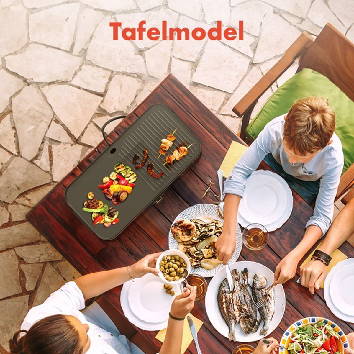 People grilling food on a table with a grill. There are plates of food on the table.