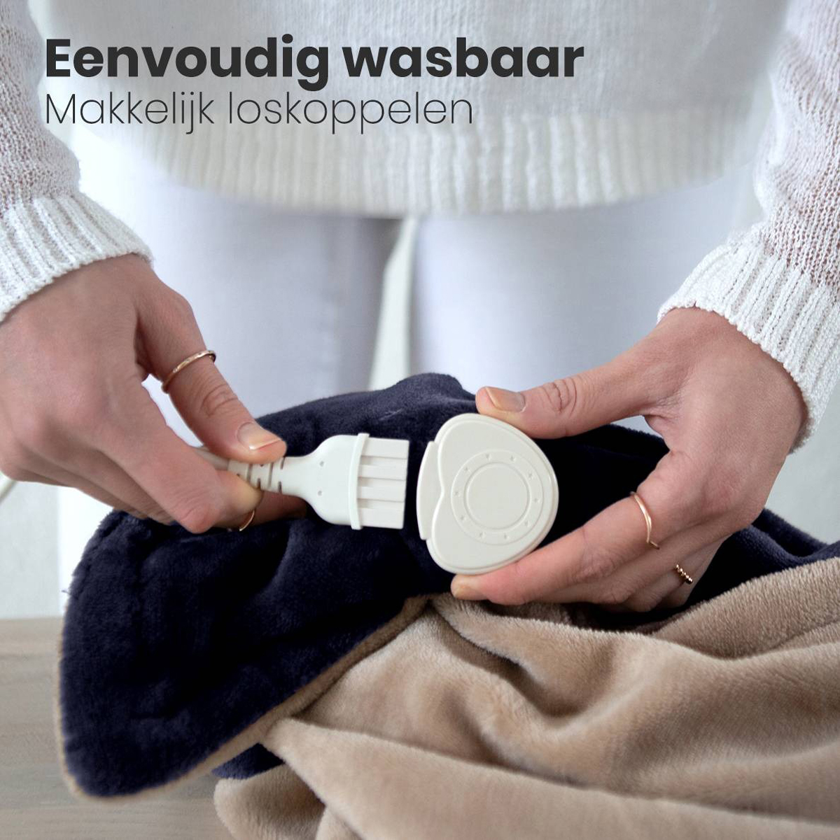 Woman plugs a white cord into a blanket. Beige and dark blue blanket. White background.