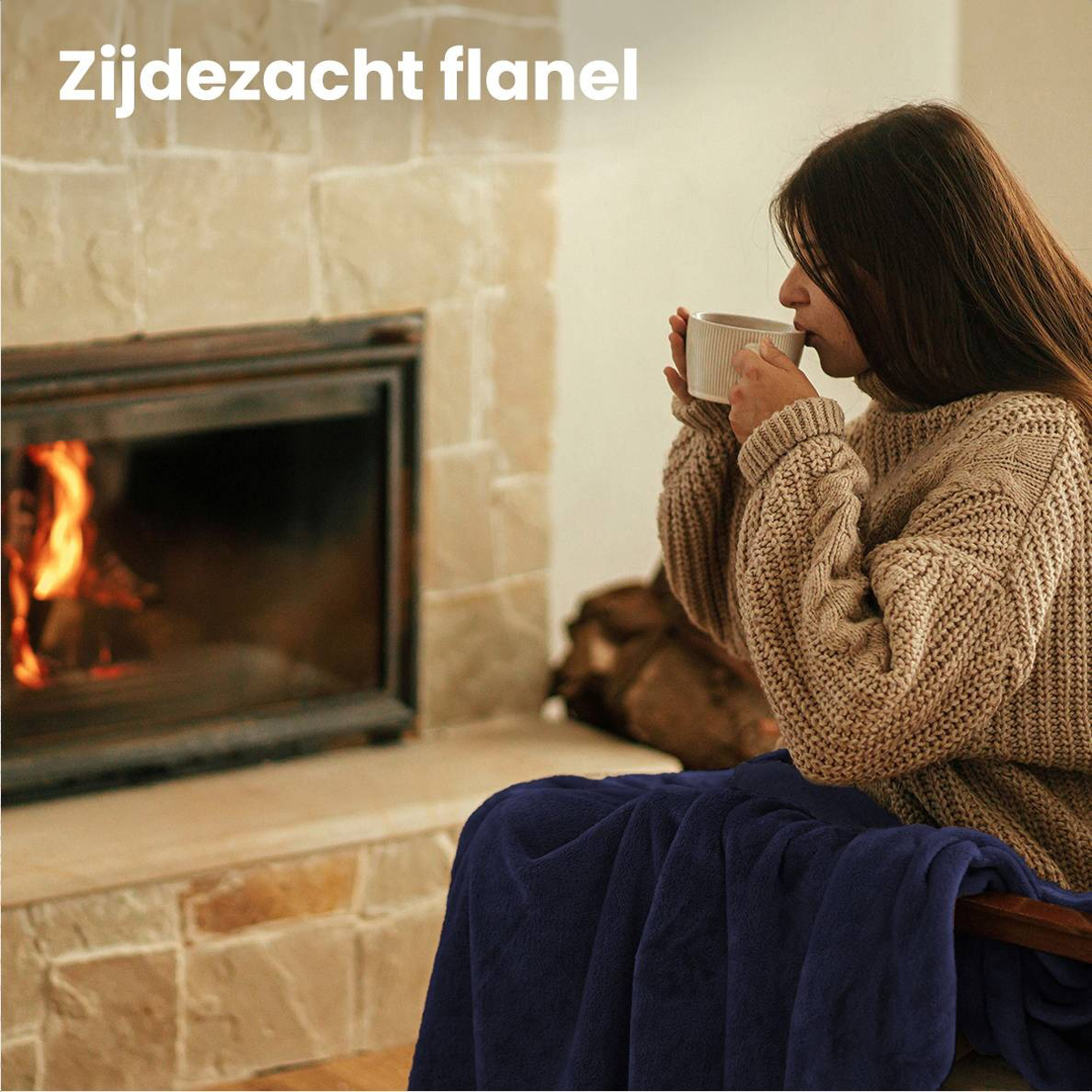 Femme en pull buvant dans une tasse devant une cheminée.