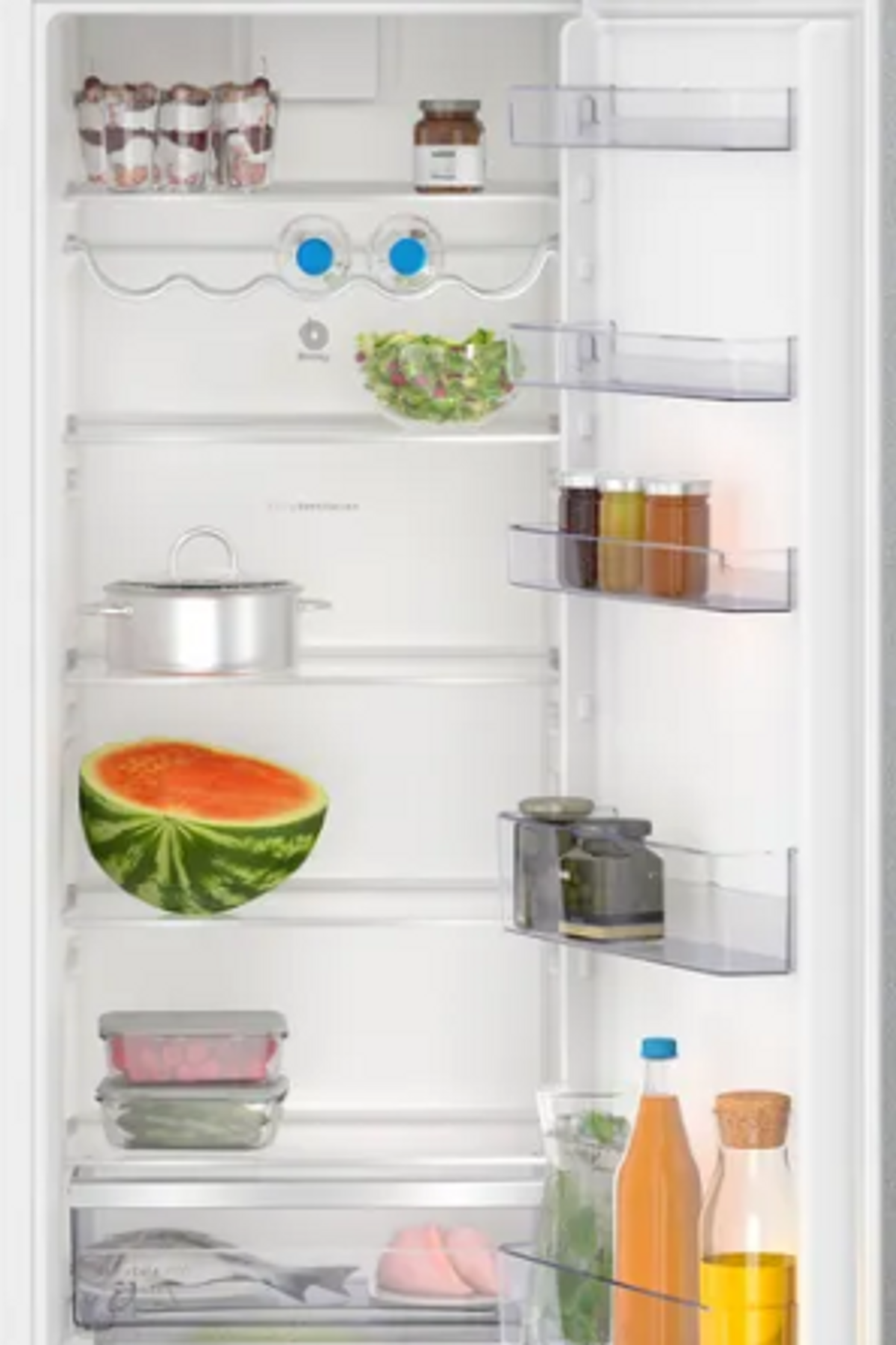 Interior de refrigerador lleno de alimentos, incluyendo frutas, verduras y frascos.