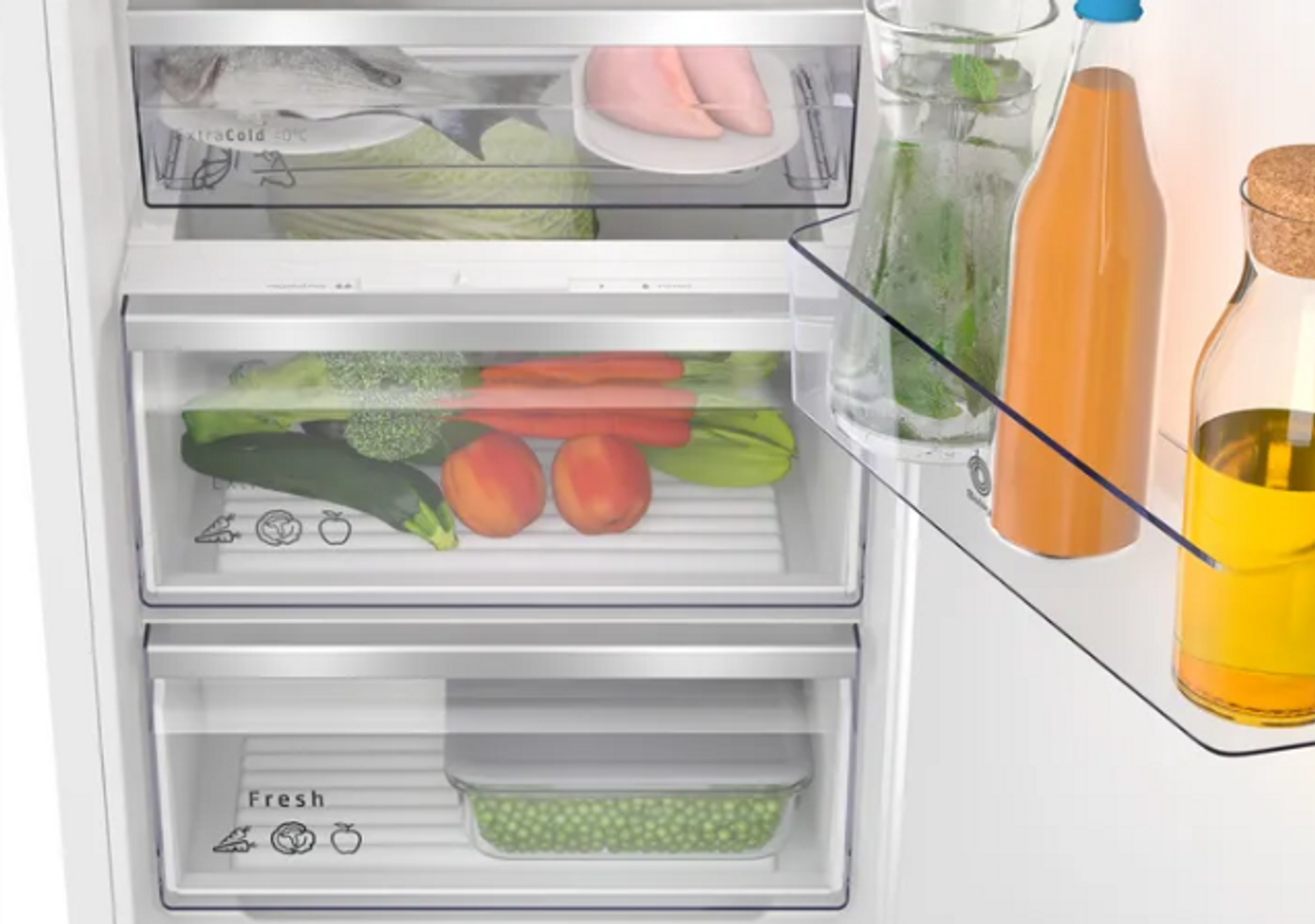 Interior de refrigerador con cajones que contienen productos frescos y bebidas embotelladas.