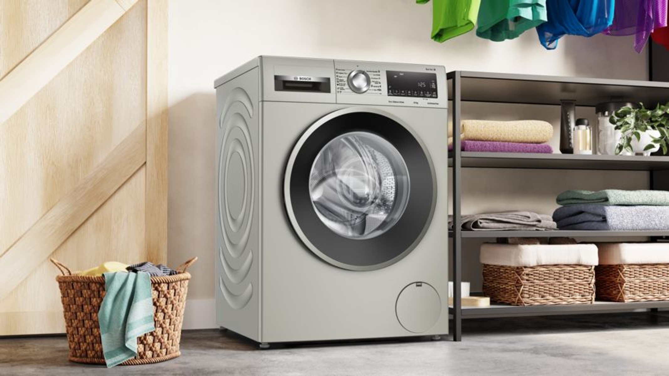 Srebrna pralka Bosch. Kosz na pranie z ubraniami znajduje się na pierwszym planie.