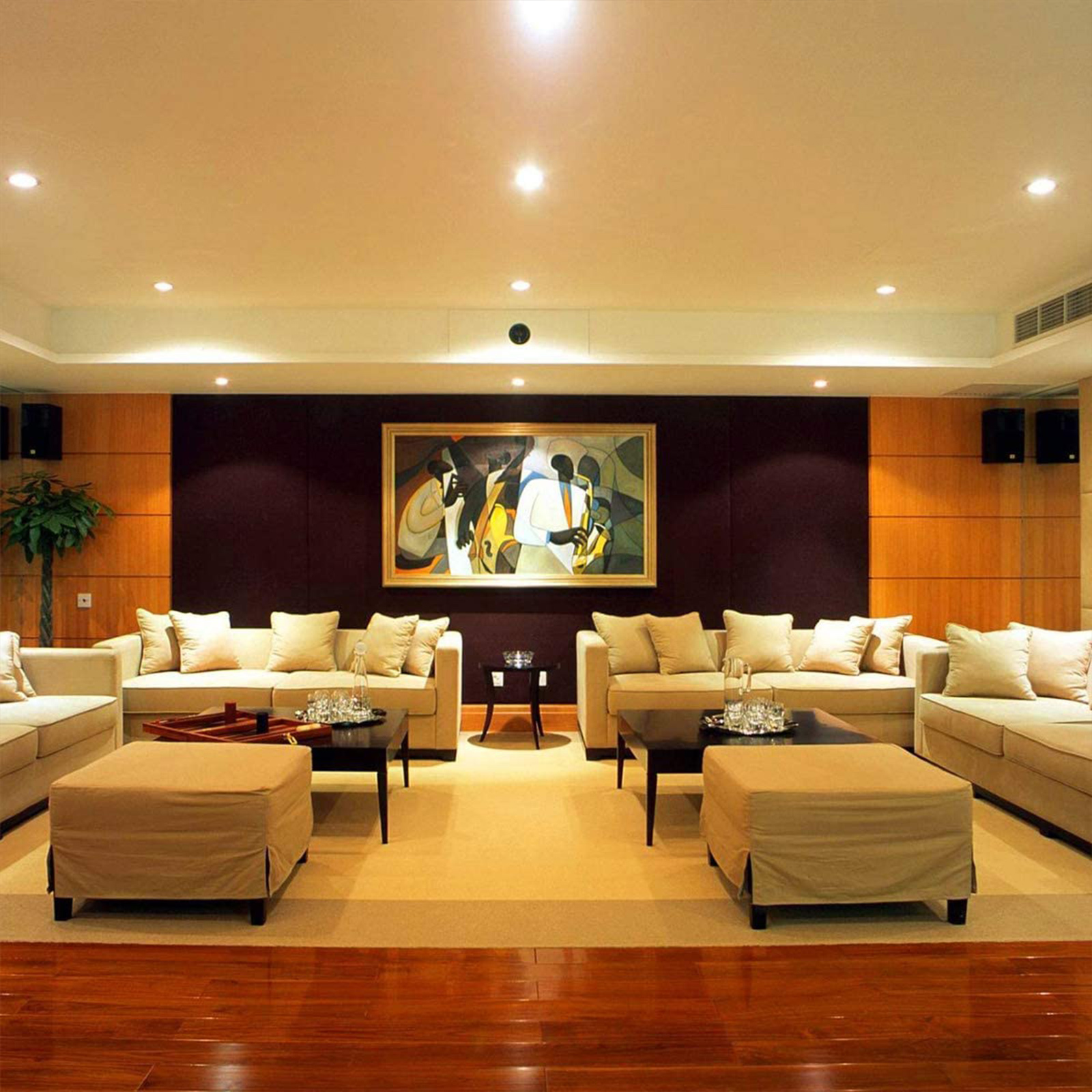 Ein luxuriöses Wohnzimmer mit beigen Sofas, einem Gemälde und dunklem Holzboden.
