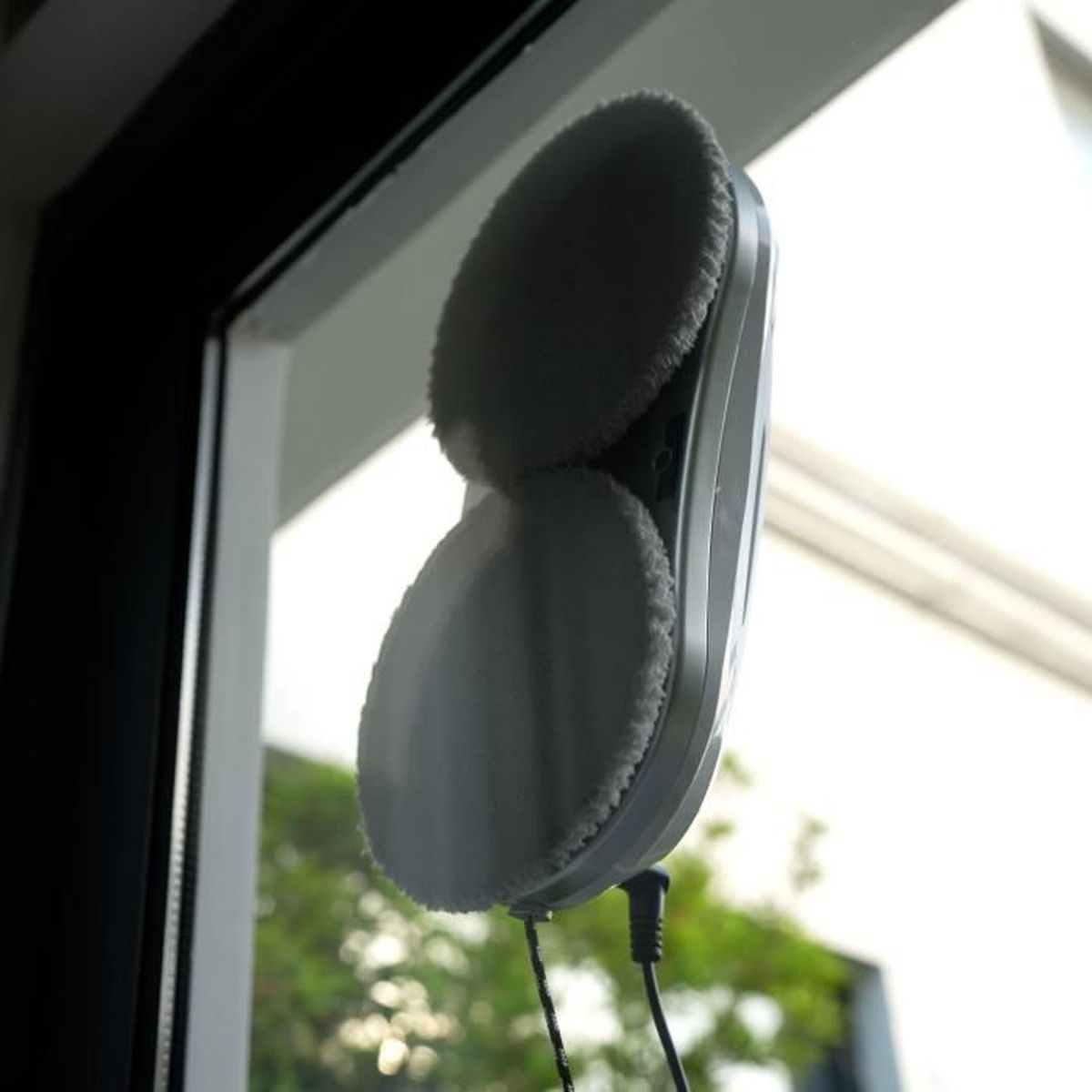 Robot do czyszczenia okien z dwoma obrotowymi nakładkami czyszczącymi na oknie.