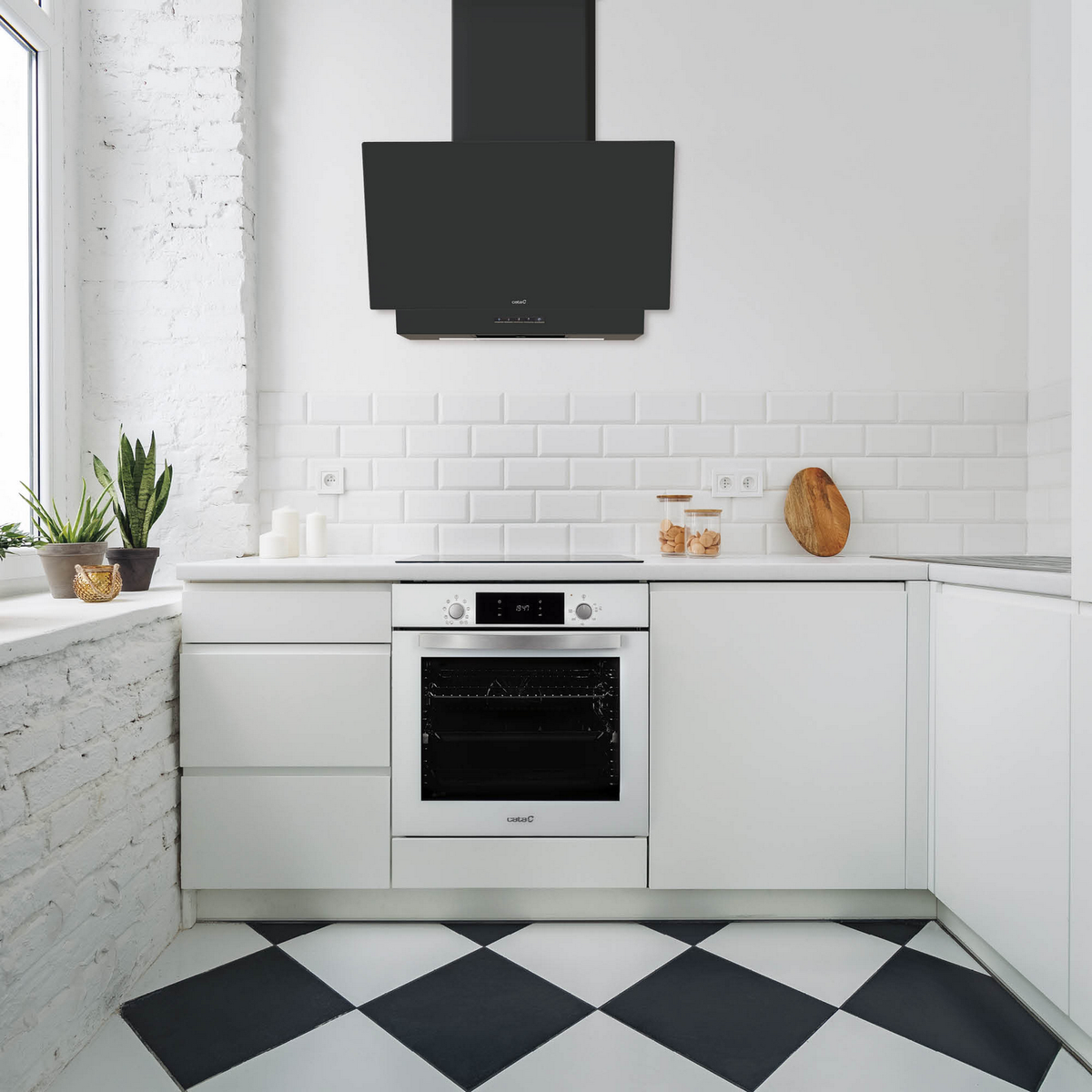 Una escena de cocina blanca con gabinetes blancos, horno, campana extractora negra y piso a cuadros blanco y negro.