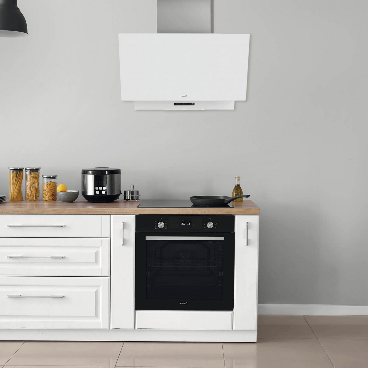 Configuración de cocina con gabinetes blancos, horno y campana. Accesorios: frascos, tostadora, sartén.