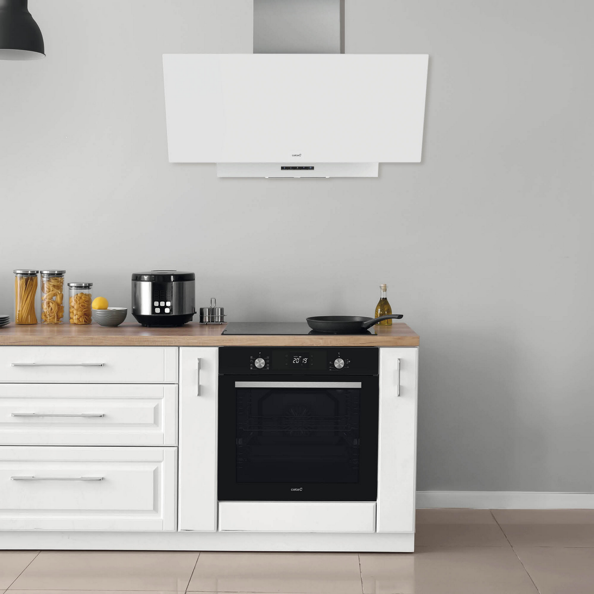 Cocina con gabinetes blancos, horno empotrado y campana extractora sobre encimera.