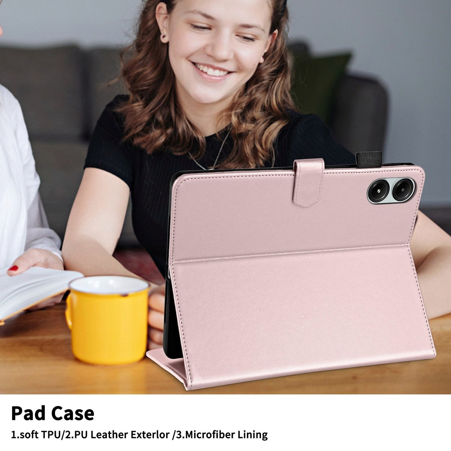 Eine Frau lächelt und hält ein Tablet in einer rosa Hülle. Das Tablet steht auf einem Tisch mit einem gelben Becher.