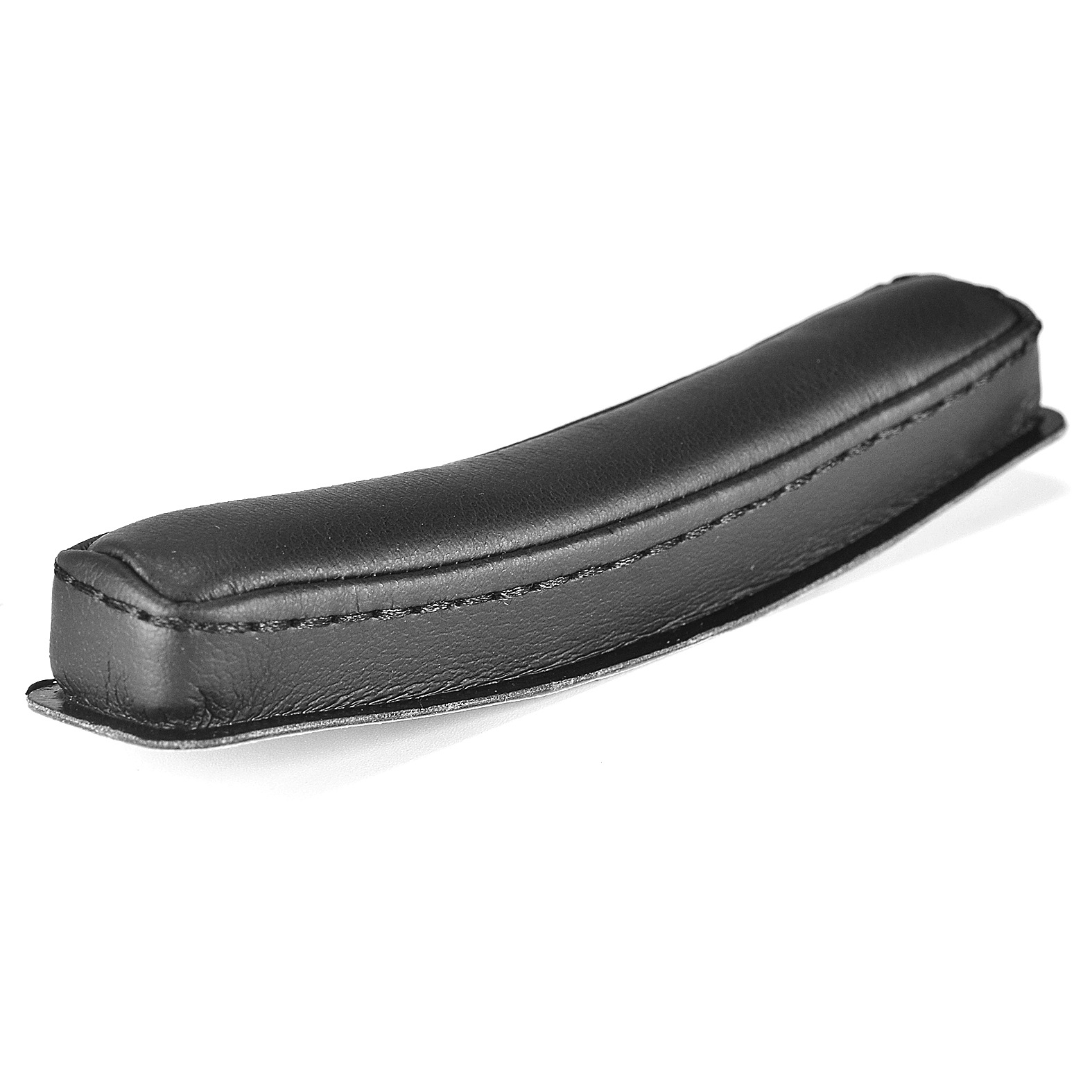 Czarna skórzana osłona podłokietnika leży na białej powierzchni. Jest zakrzywiona.