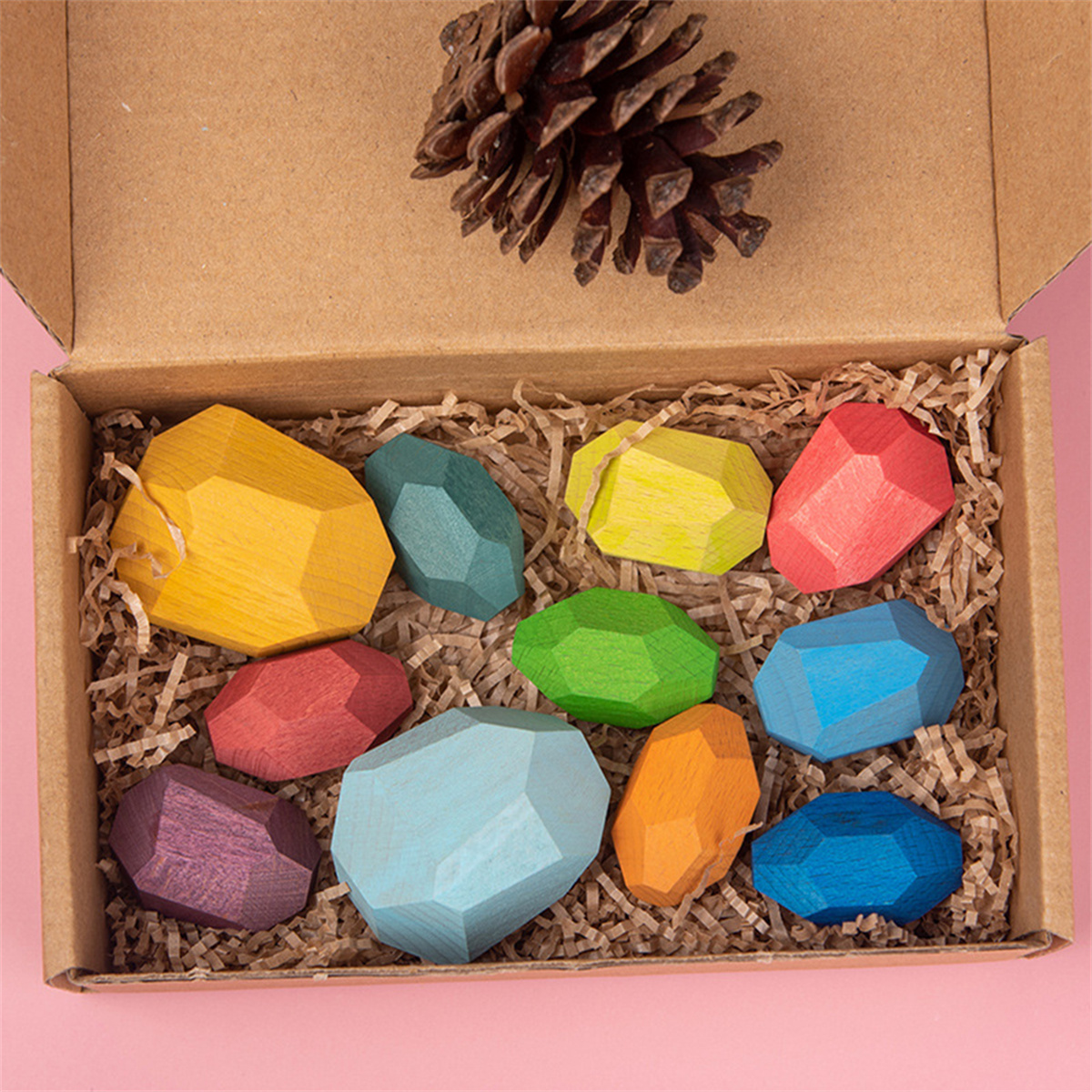 Holzspielzeugblöcke in einer Box, verschiedene Farben. Eine Tannenzapfen liegt oben drauf.