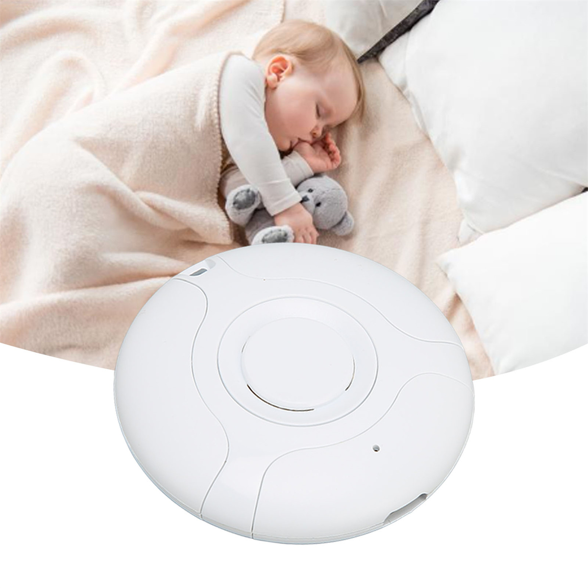 Ein Baby, das mit einem Teddybären neben einem weißen Babyphone schläft.