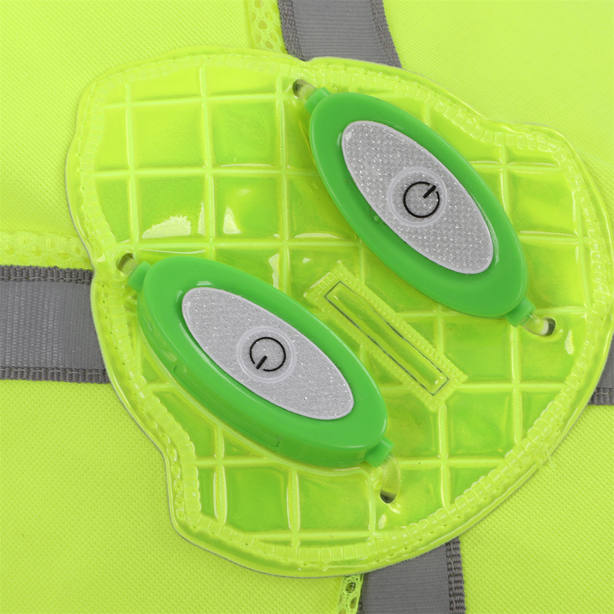 Zwei grüne LED-Leuchten mit Knopf, an gelber Weste befestigt.