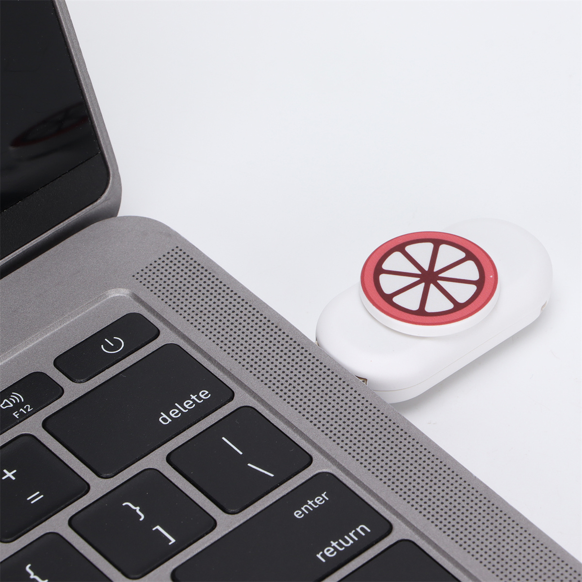 Laptop-Tastatur mit rotem kreisförmigem Knopf. Weißer Hintergrund.