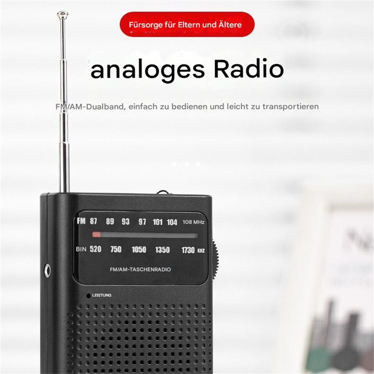 Ein schwarzes analoges Radio wird gezeigt. Es hat einen Lautsprecher, einen Abstimmknopf und eine Teleskopantenne. Text ist drauf.