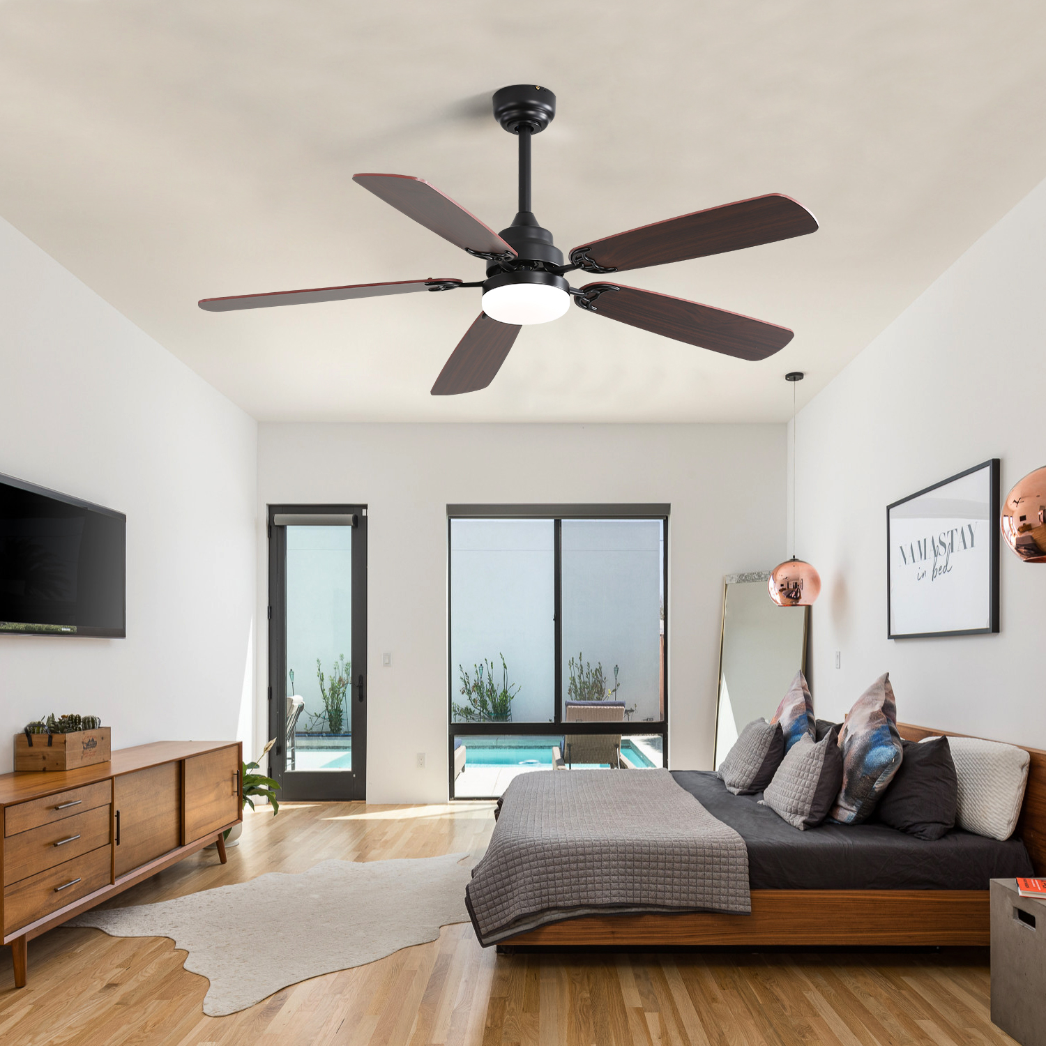 Schlafzimmer mit Deckenventilator, Bett und Holzmöbeln. Weiße Wände, großes Fenster, Kunstwerk.