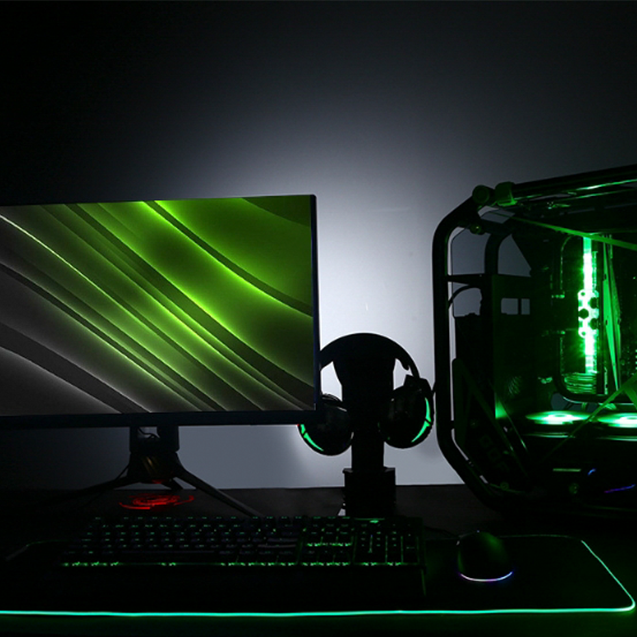 Gaming-Setup mit grün beleuchtetem Computer und Peripheriegeräten.