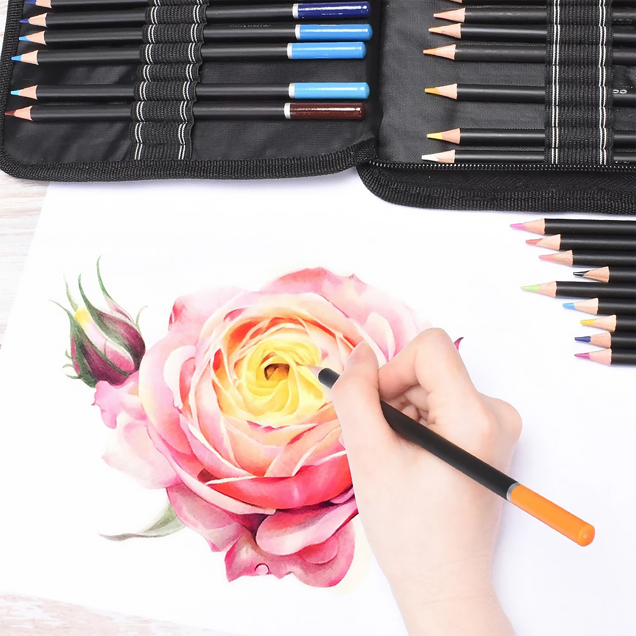 Hand zeichnet eine Rose mit einem Farbstift auf weißem Papier, mit Stiften und Etui.