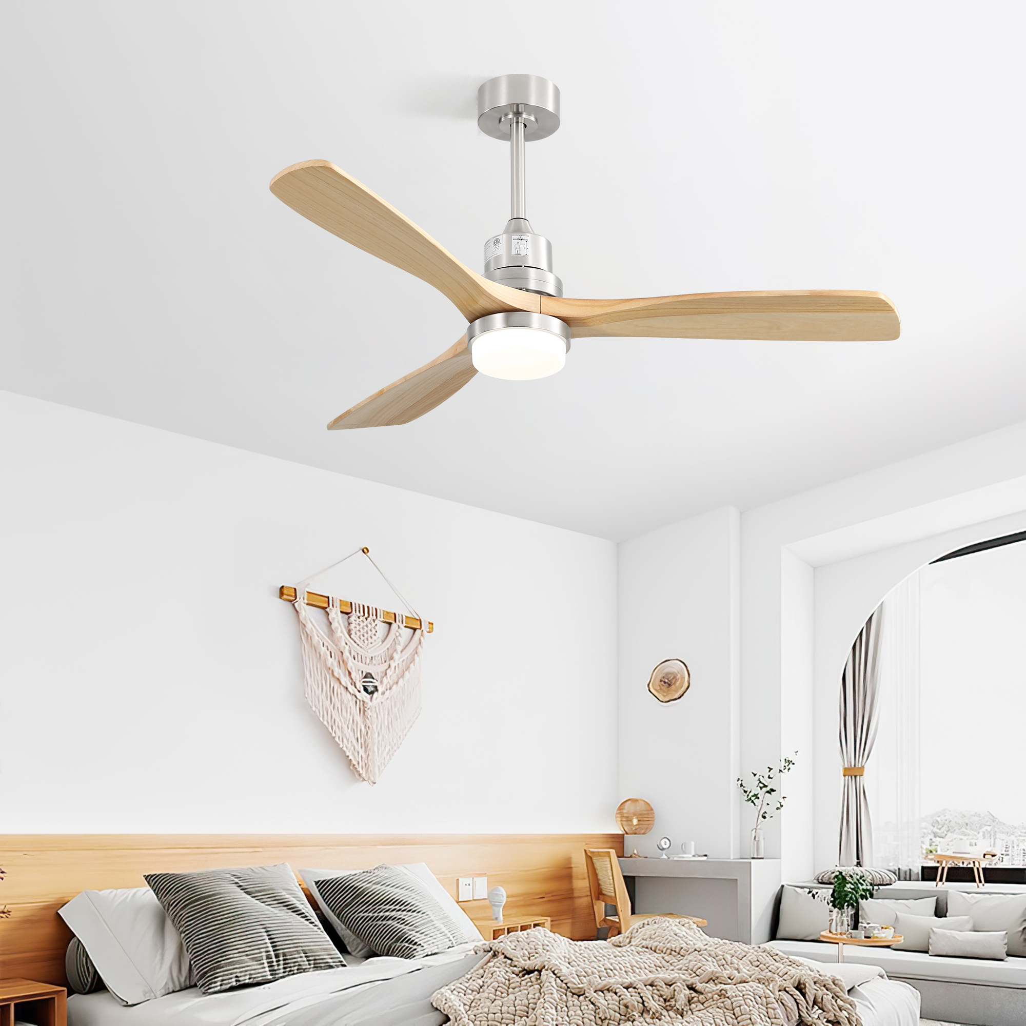 Weißer Deckenventilator mit Holzflügeln hängt in einem Schlafzimmer mit Bett und Makramee-Wanddeko.