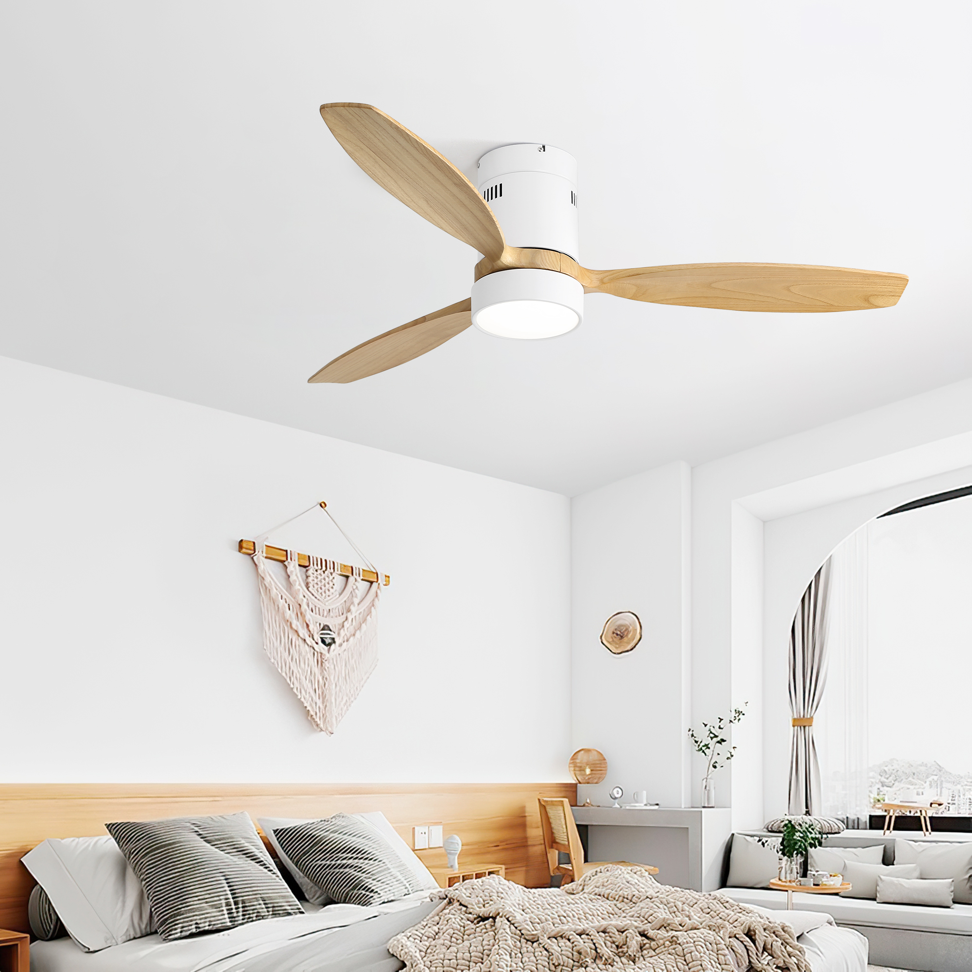 Ein weißer Deckenventilator mit drei Holzblättern. Er ist an einer weißen Decke in einem Schlafzimmer montiert.