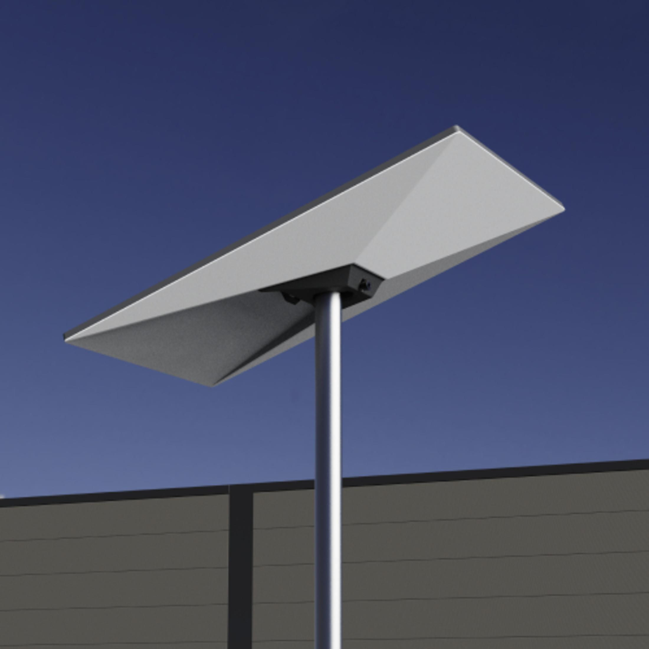 Modernes Solarpanel auf einem Pfahl vor blauem Himmel und grauem Gebäude.