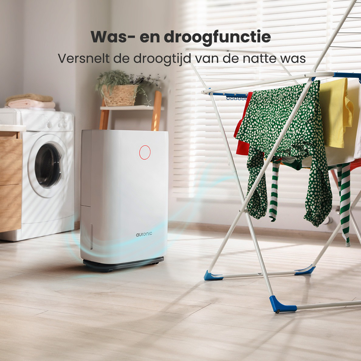 Een witte luchtreiniger naast een wasmachine. Kleding op een droogrek op de achtergrond.