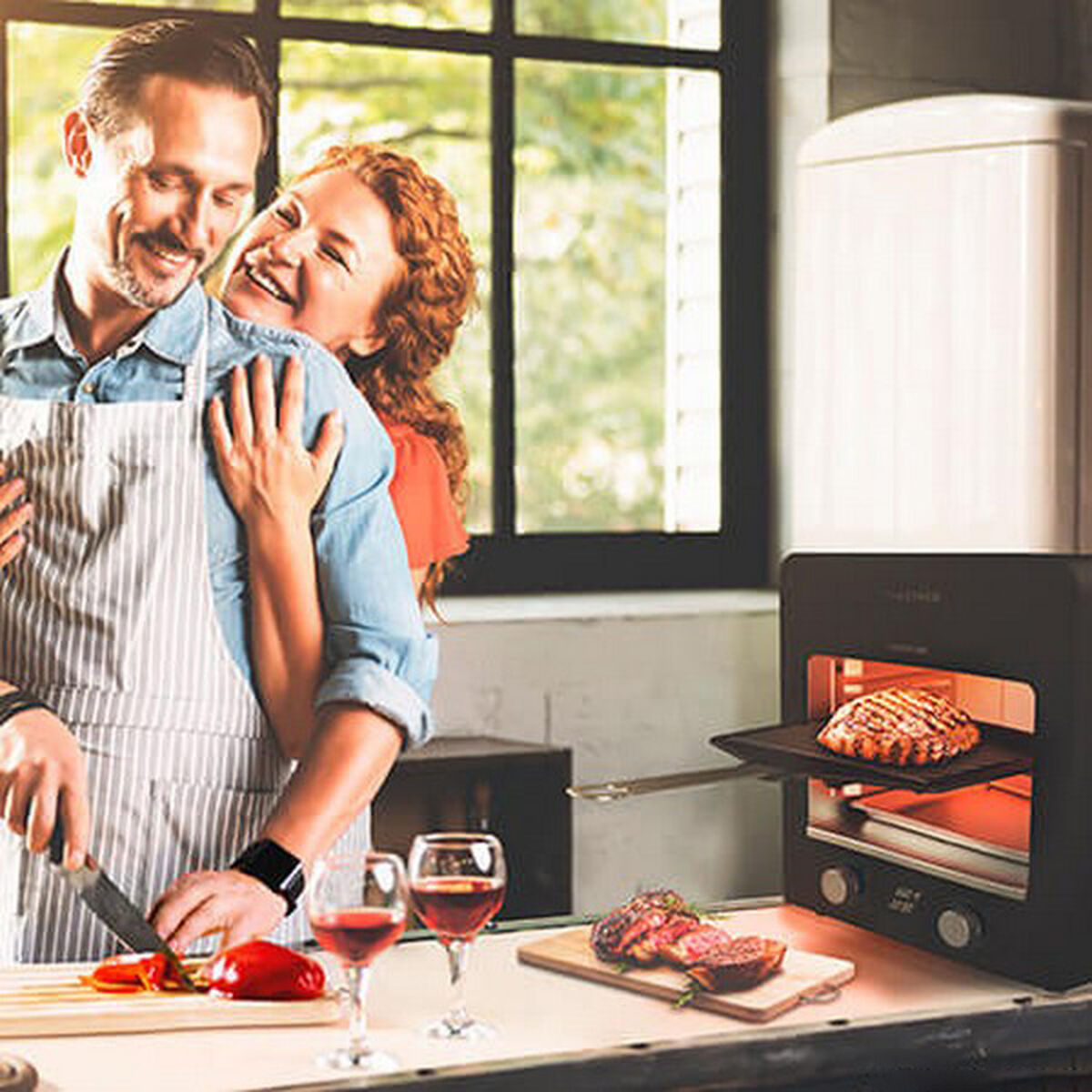 Coppia che cucina in cucina. Uomo taglia cibo, donna lo abbraccia. Cibo grigliato in forno.