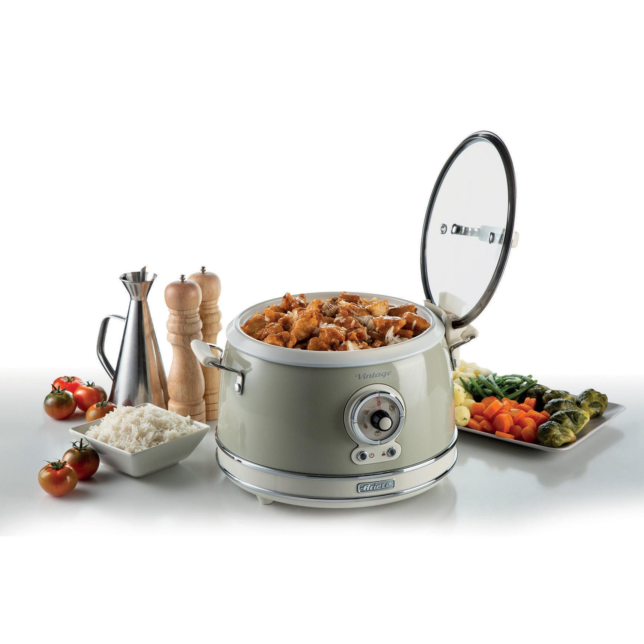 Wolnowar w stylu vintage z jedzeniem, warzywami i ryżem. Przezroczysta pokrywa otwarta. Białe tło.