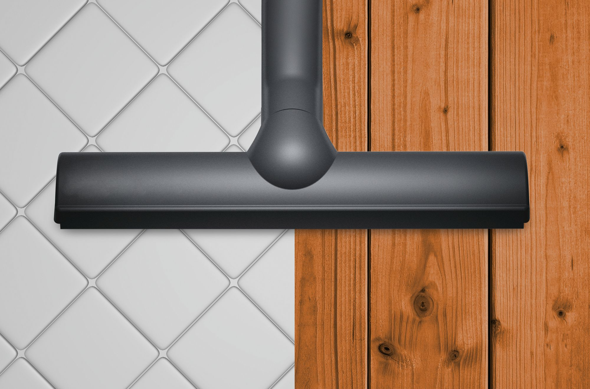 Czarna głowica odkurzacza nad białymi kafelkami i drewnianą podłogą. Głowica jest nad obiema powierzchniami.